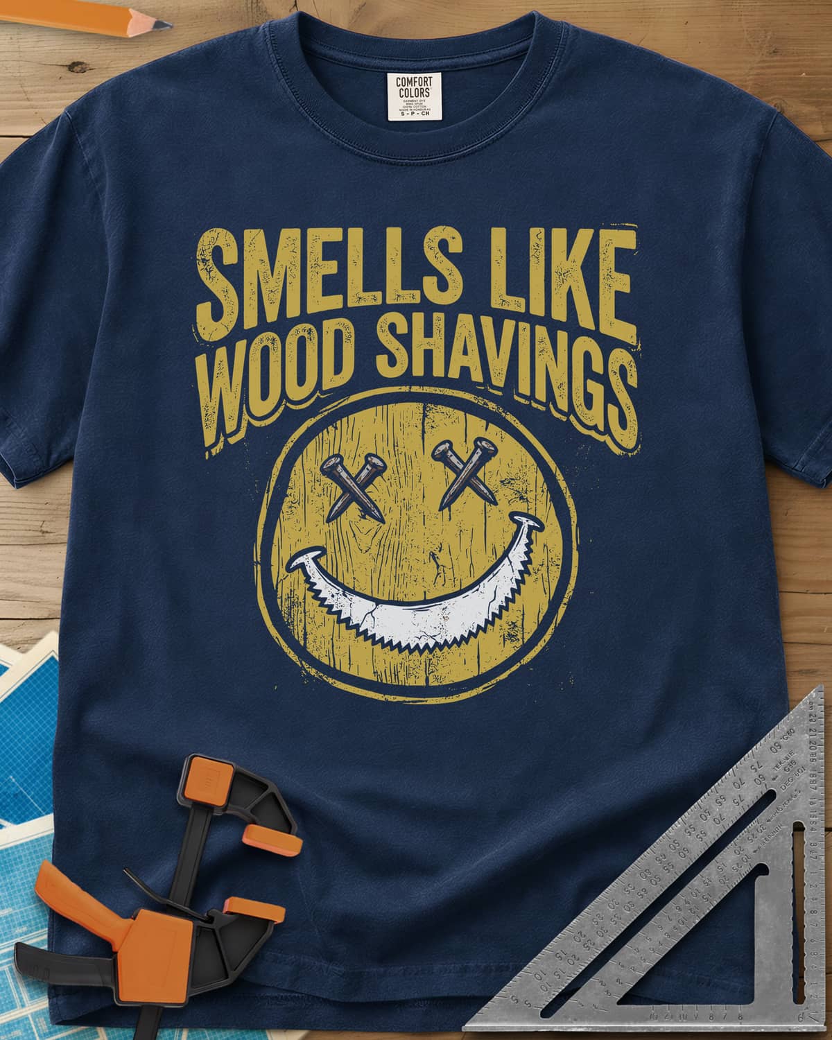 Smells Like Wood Shavings heavyweight tee in Navy, a worn yellow smiley with nails for eyes and a saw blade grin