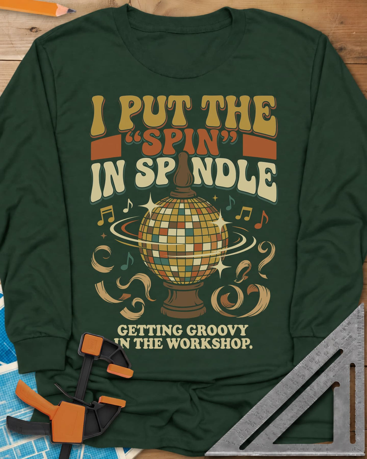 Spin in Spindle long sleeve shirt in Forest Green, a disco ball on a turned wooden base with notes and shavings