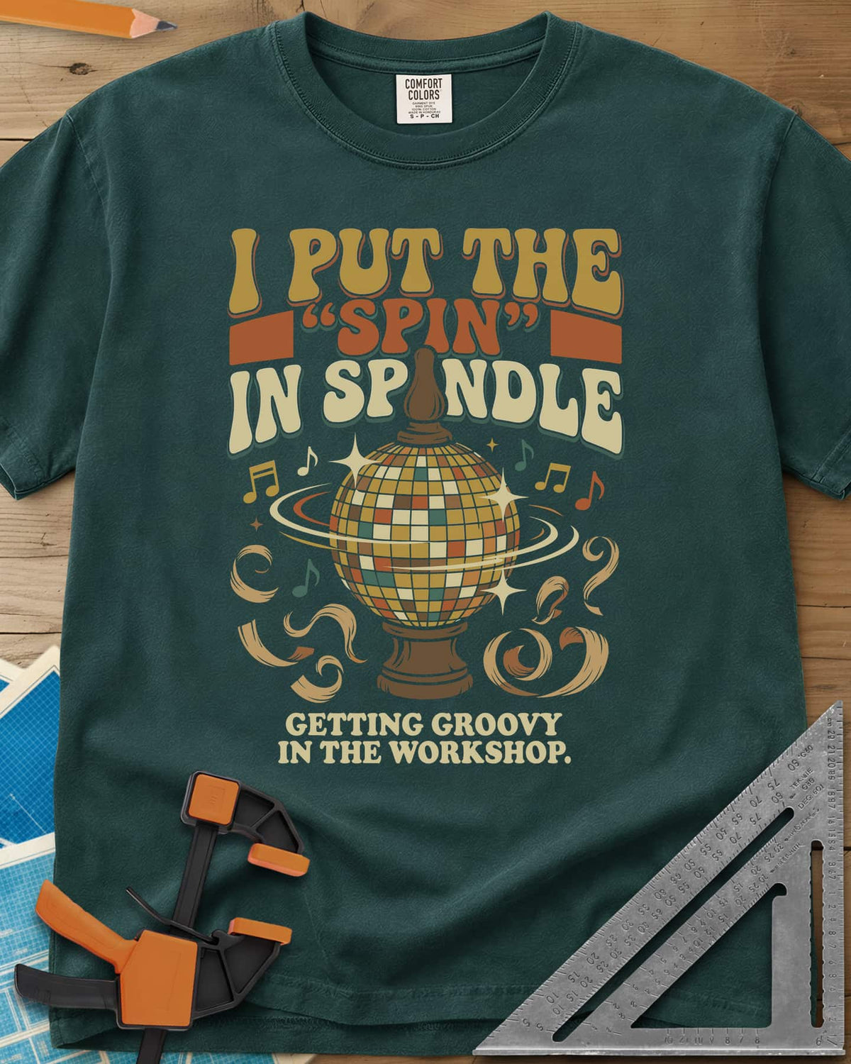 Spin in Spindle heavyweight tee in Blue Spruce, a disco ball on a turned wooden base with notes and shavings