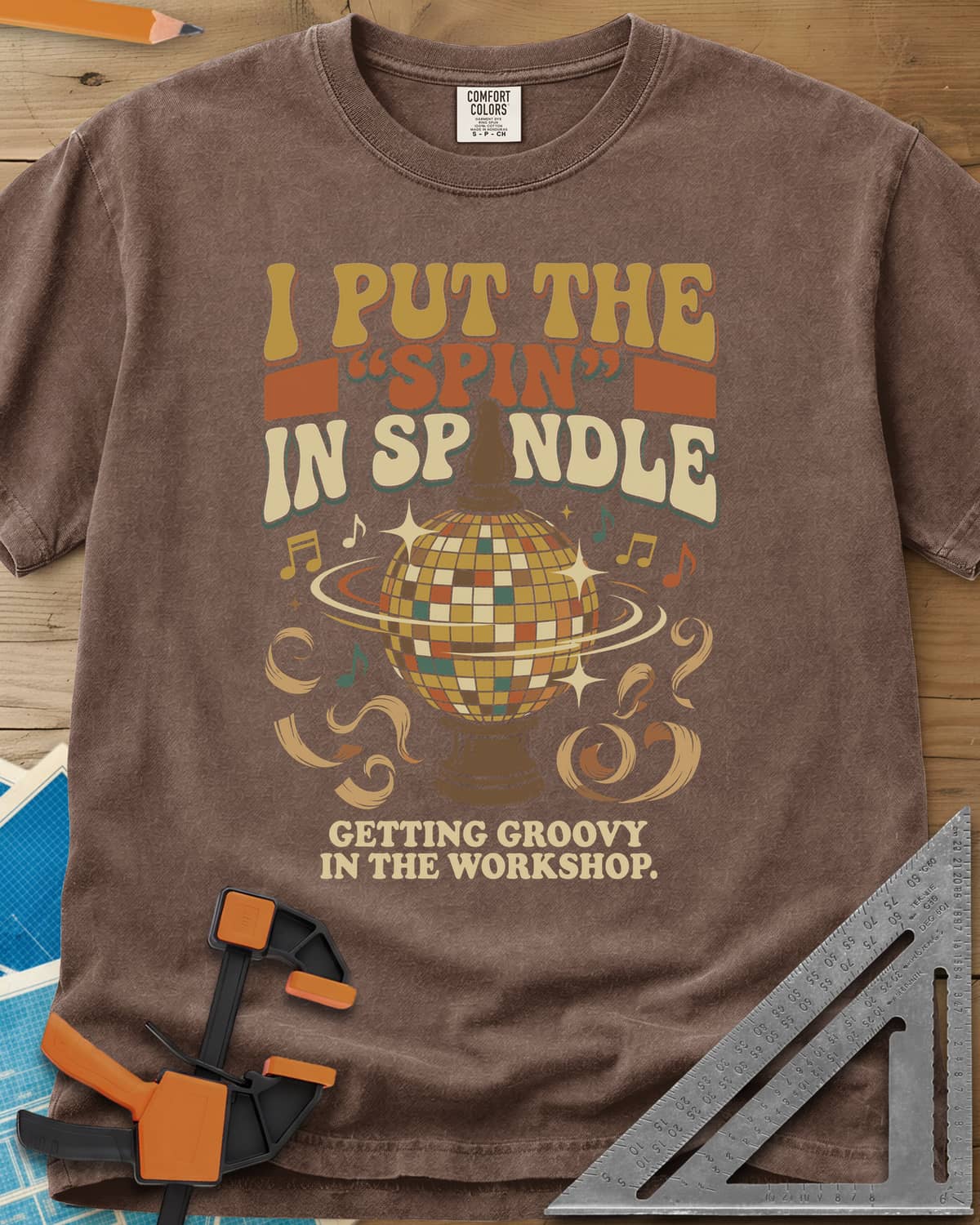 Spin in Spindle heavyweight tee in Espresso, a disco ball on a turned wooden base with notes and shavings