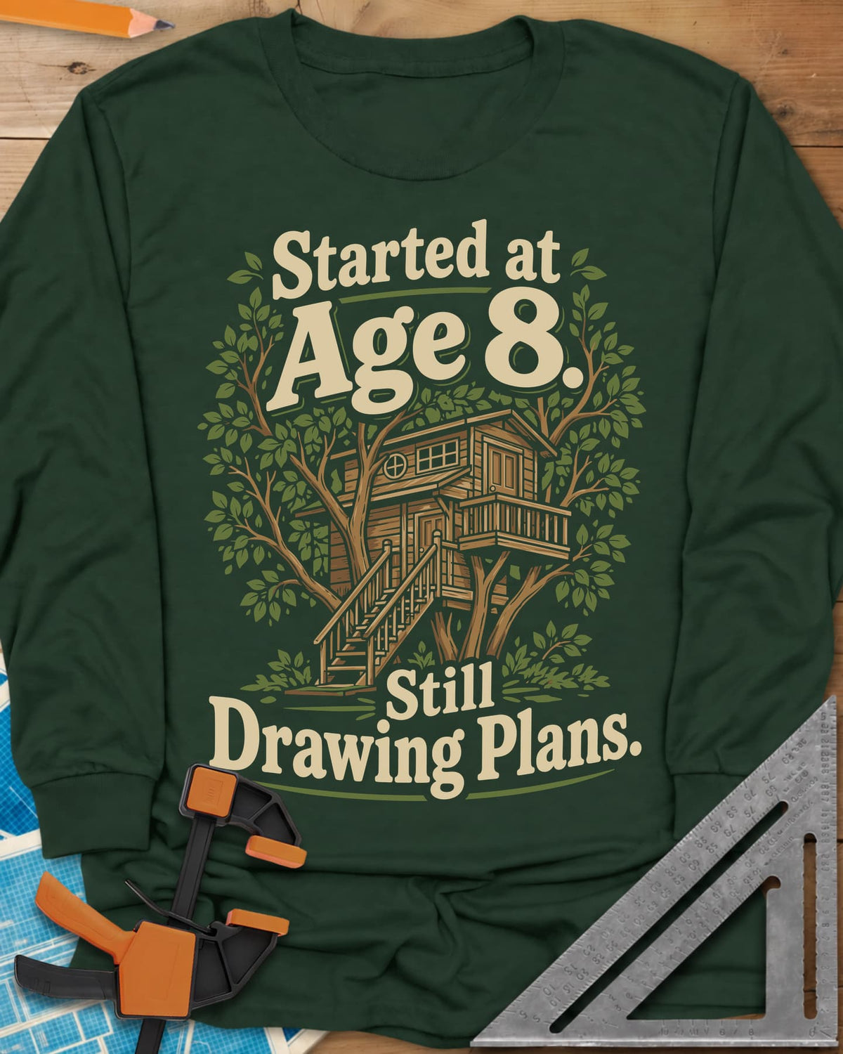 Started At Age 8 long sleeve shirt in Forest Green, a wooden treehouse with a deck and stairs among green leaves