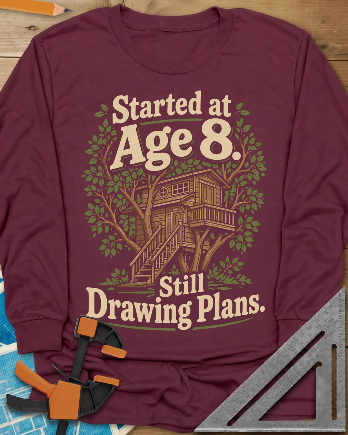 Started At Age 8 long sleeve shirt in Maroon, a wooden treehouse with a deck and stairs among green leaves