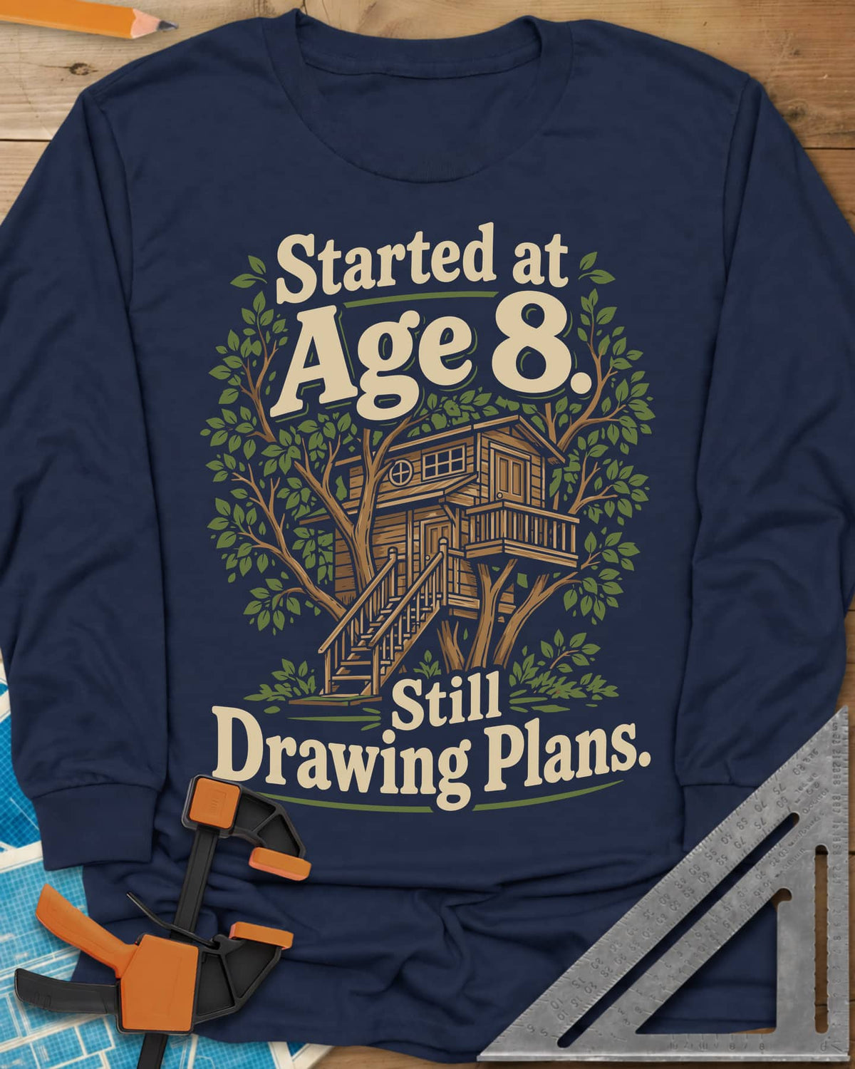 Started At Age 8 long sleeve shirt in Navy, a wooden treehouse with a deck and stairs among green leaves
