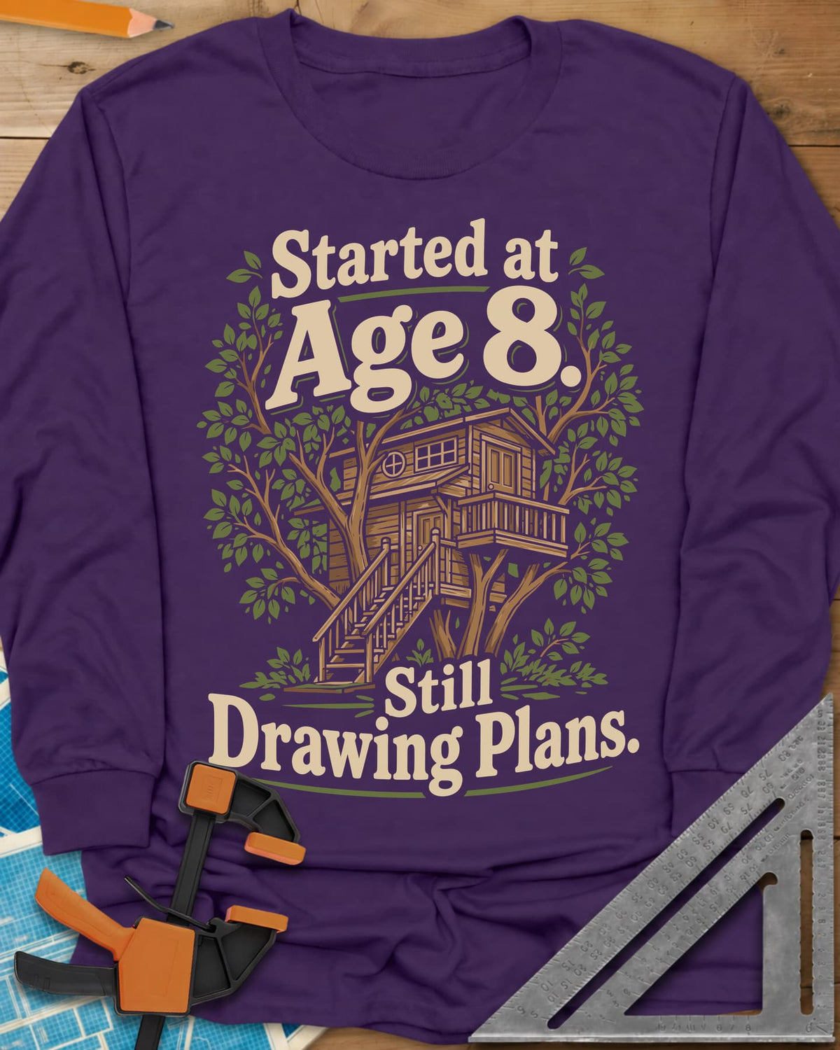 Started At Age 8 long sleeve shirt in Purple, a wooden treehouse with a deck and stairs among green leaves