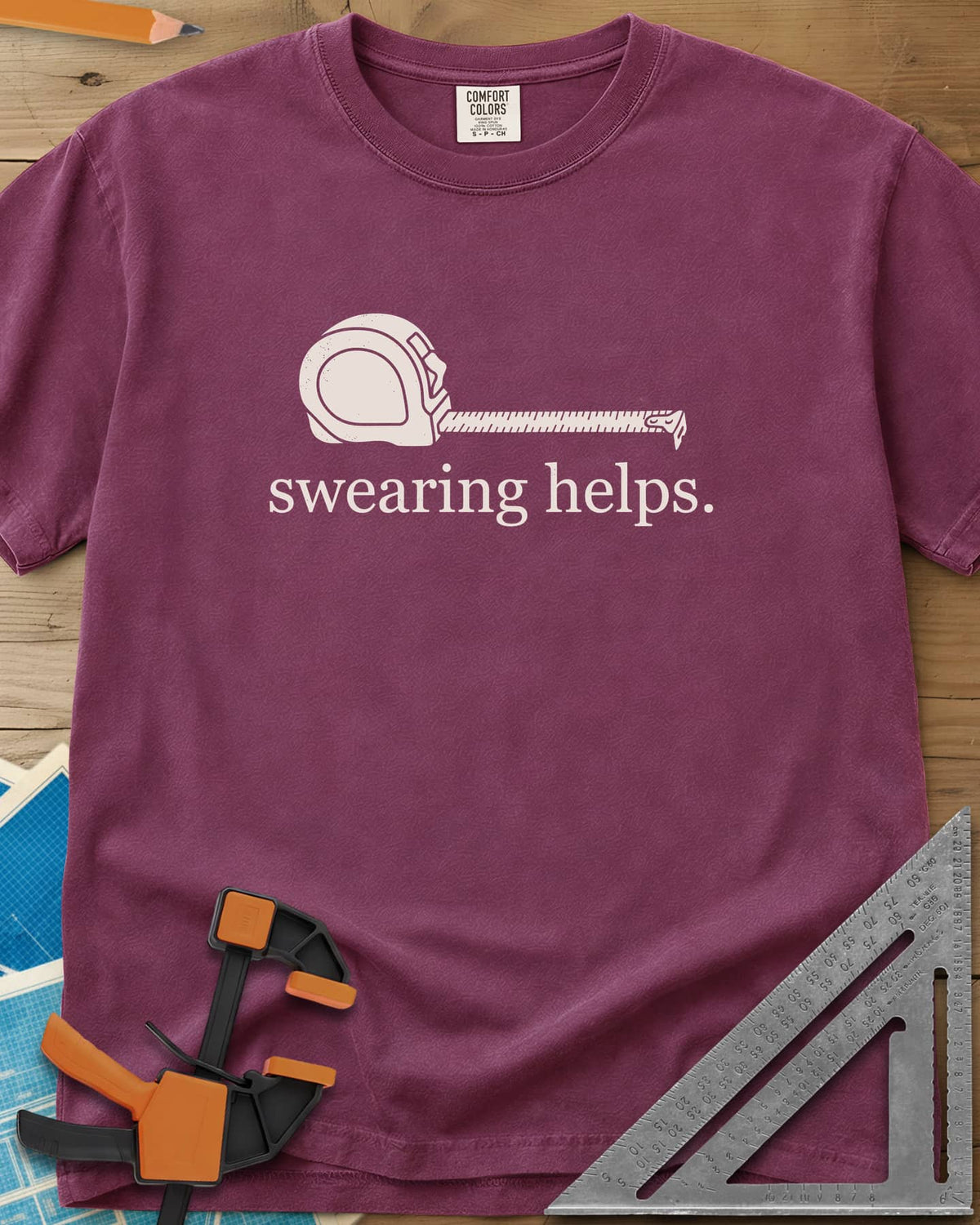 Swearing Helps heavyweight tee in Berry, a tape measure with its blade pulled out above small lowercase type