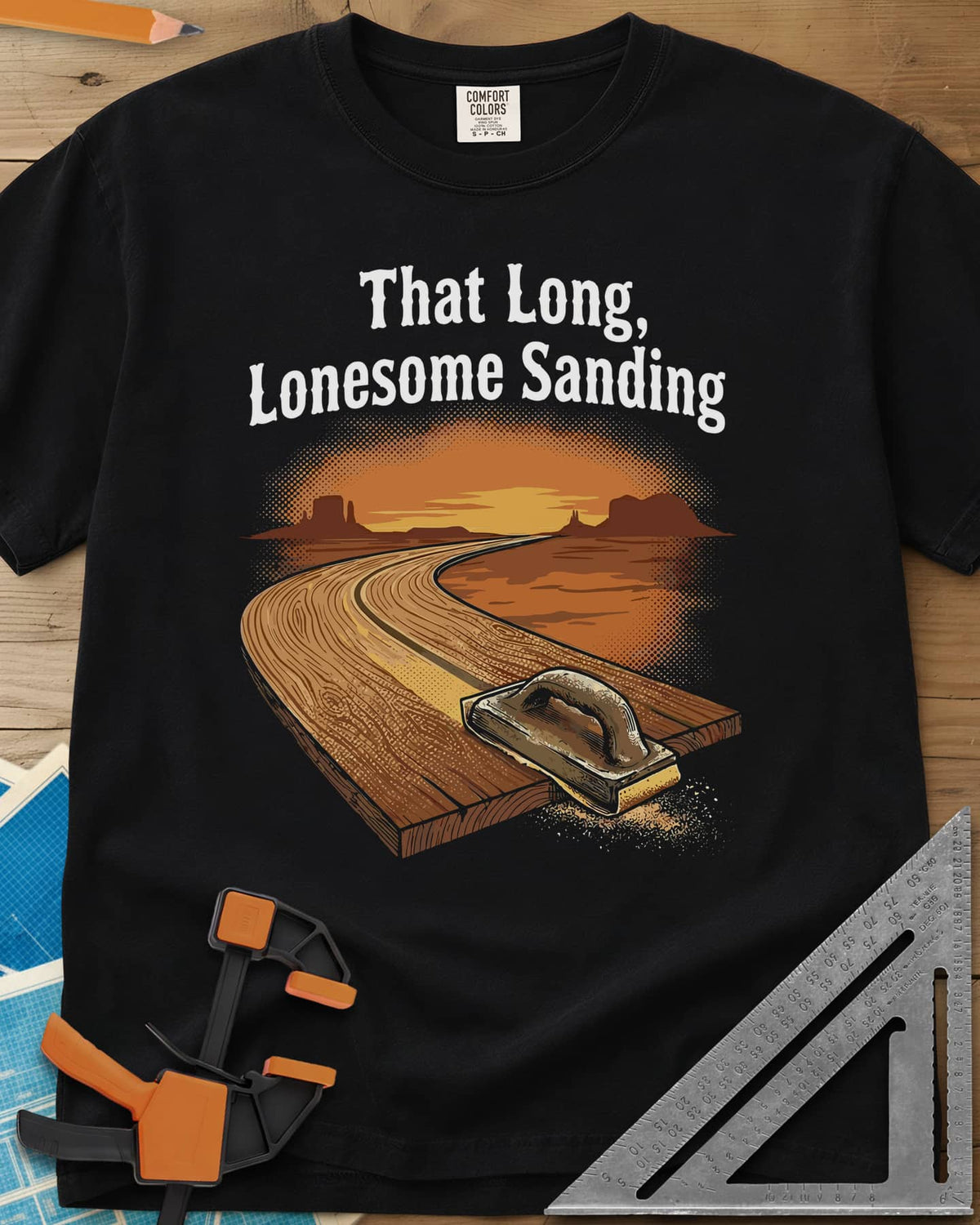 That Long, Lonesome Sanding heavyweight tee in Black, a plank road winding through a desert sunset with a sanding block