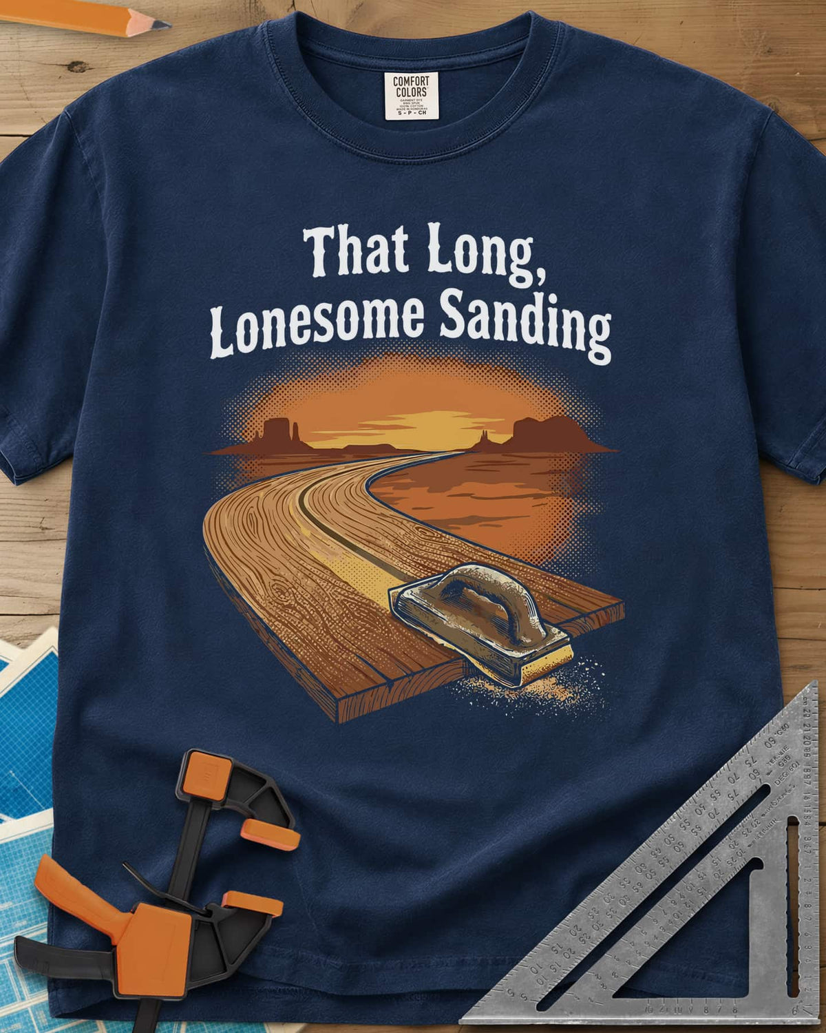 That Long, Lonesome Sanding heavyweight tee in Navy, a plank road winding through a desert sunset with a sanding block