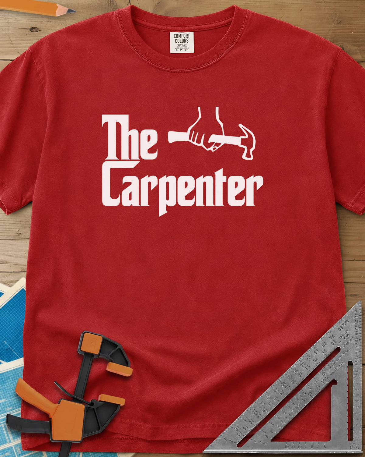 The Carpenter heavyweight tee in Red, film-poster style lettering with a fist gripping a hammer