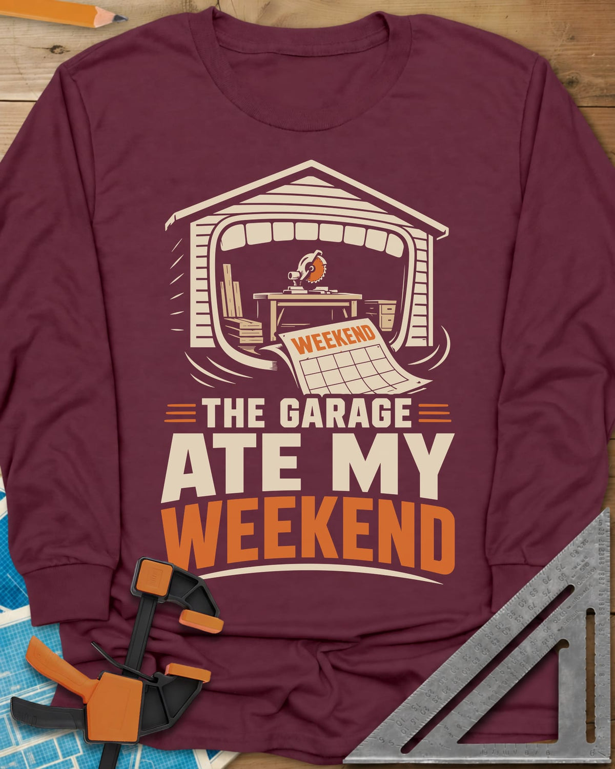 The Garage Ate My Weekend long sleeve shirt in Maroon, a garage with a miter saw inside and a calendar page flying in