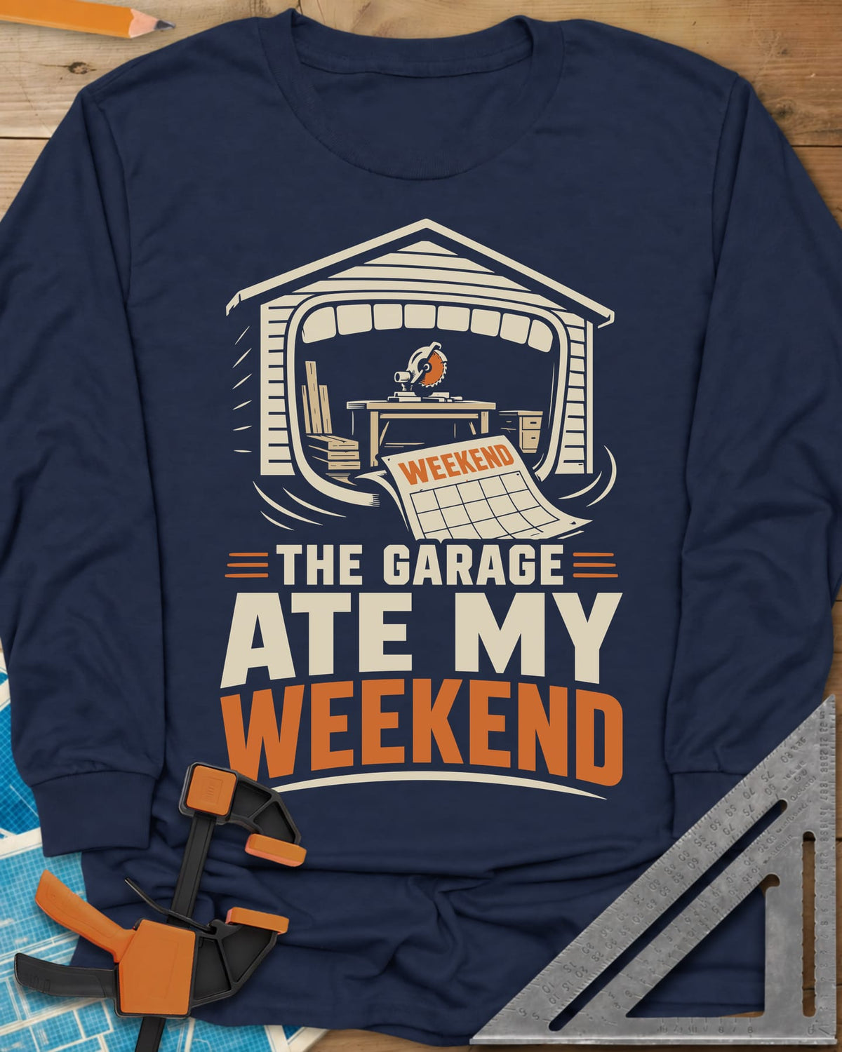 The Garage Ate My Weekend long sleeve shirt in Navy, a garage with a miter saw inside and a calendar page flying in