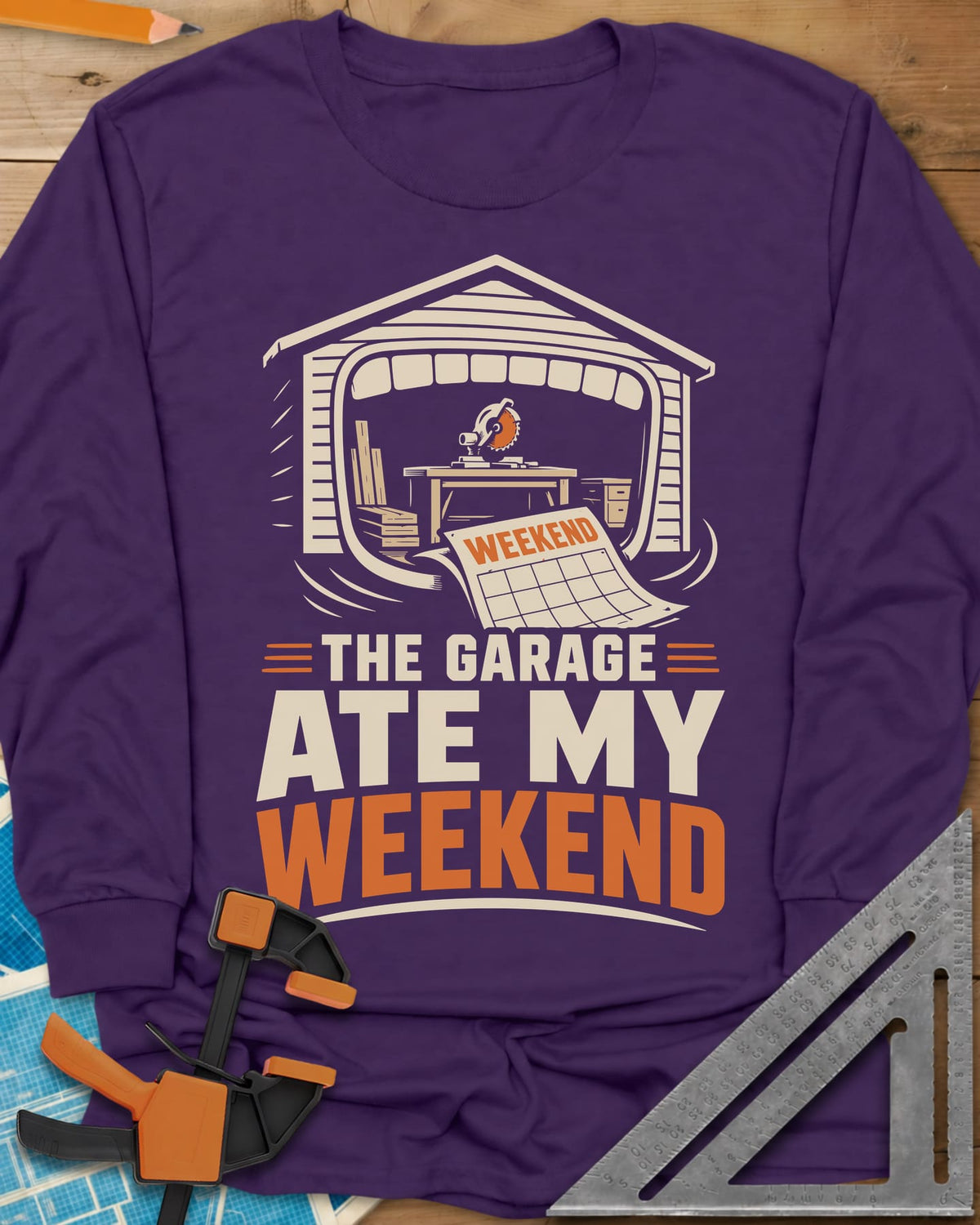 The Garage Ate My Weekend long sleeve shirt in Purple, a garage with a miter saw inside and a calendar page flying in