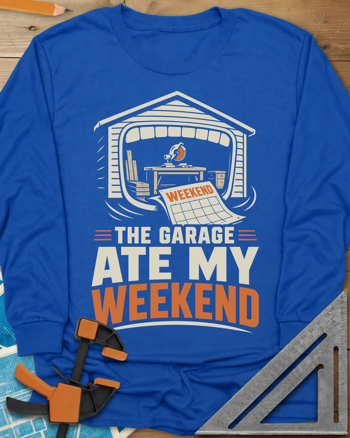 The Garage Ate My Weekend long sleeve shirt in Royal, a garage with a miter saw inside and a calendar page flying in