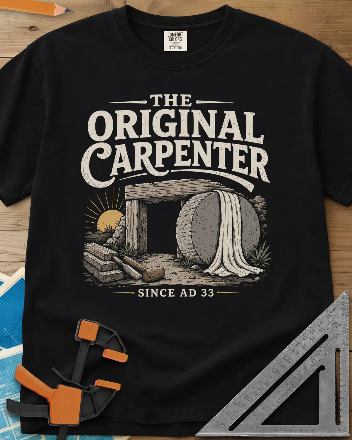 The Original Carpenter heavyweight tee in Black, an empty tomb at sunrise with planks, a mallet and a chisel