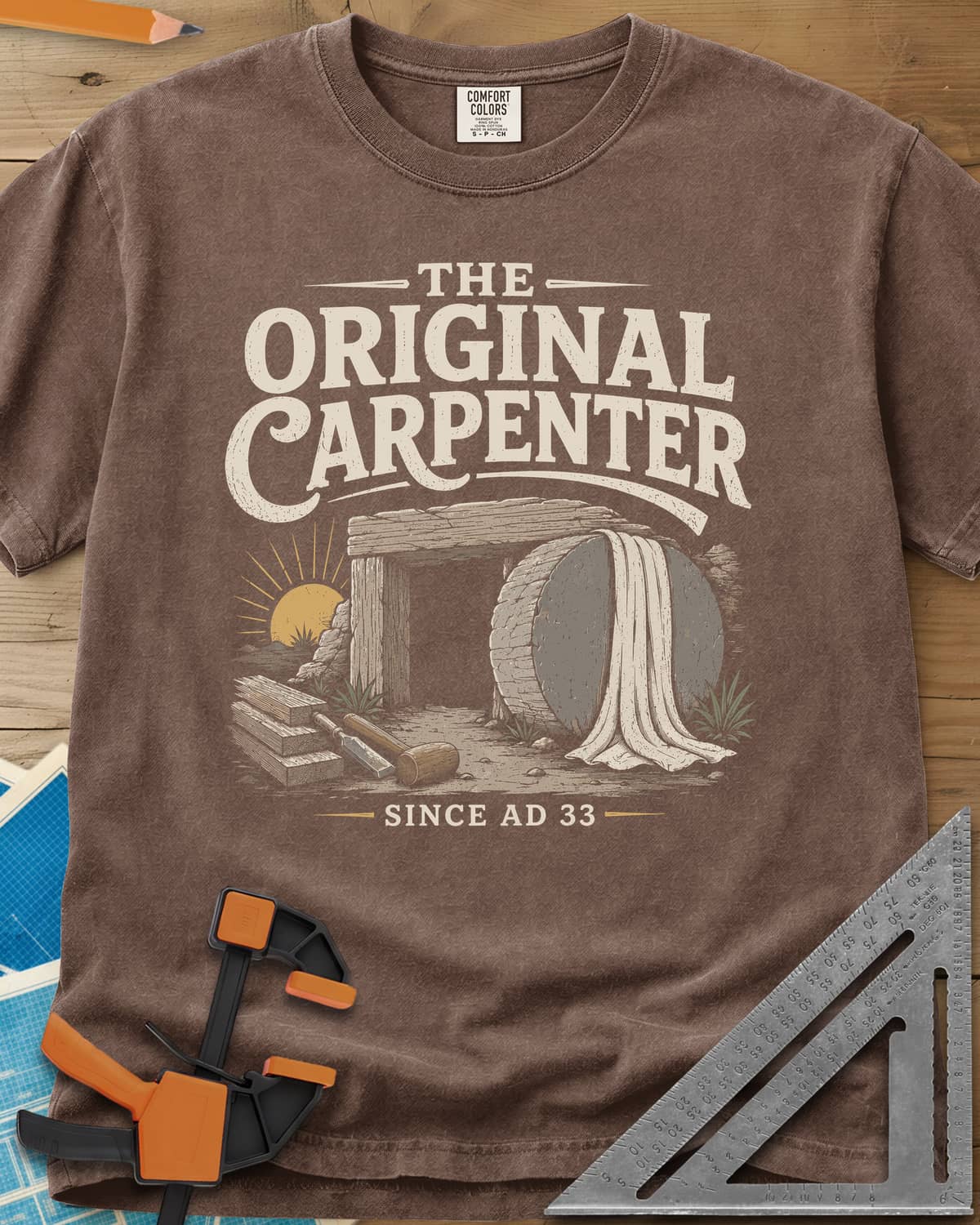 The Original Carpenter heavyweight tee in Espresso, an empty tomb at sunrise with planks, a mallet and a chisel