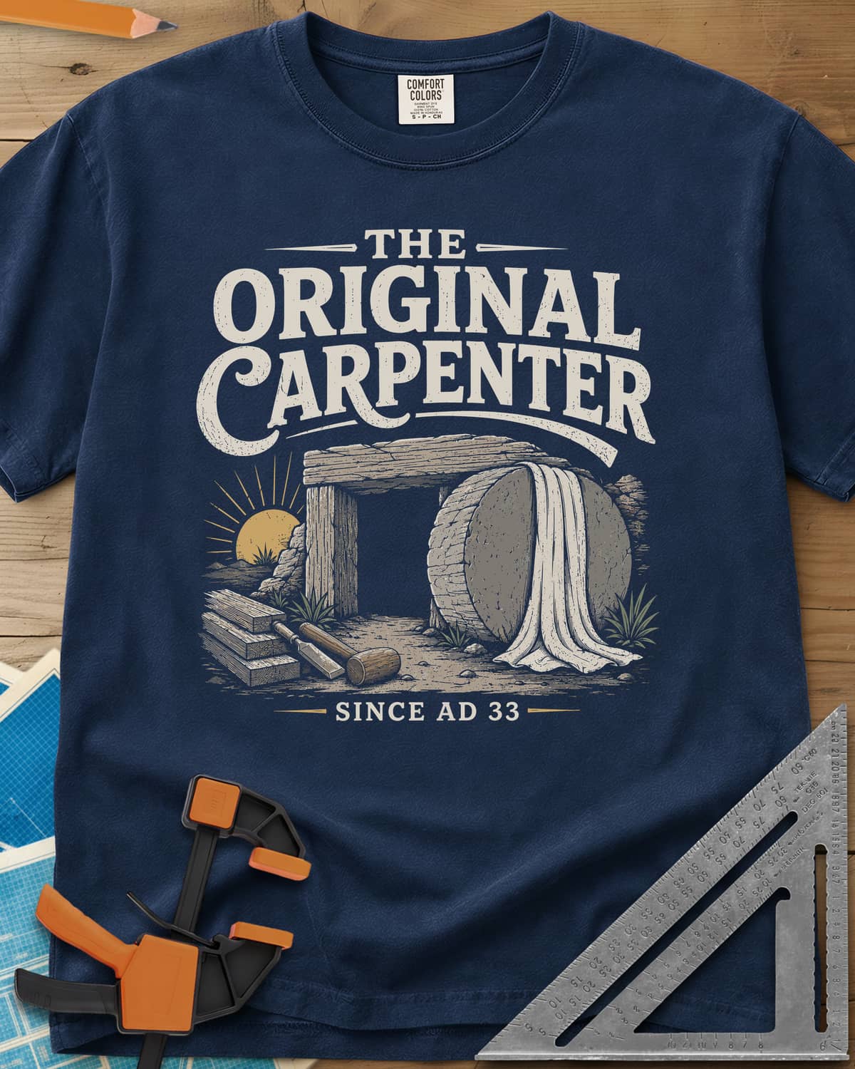 The Original Carpenter heavyweight tee in Navy, an empty tomb at sunrise with planks, a mallet and a chisel