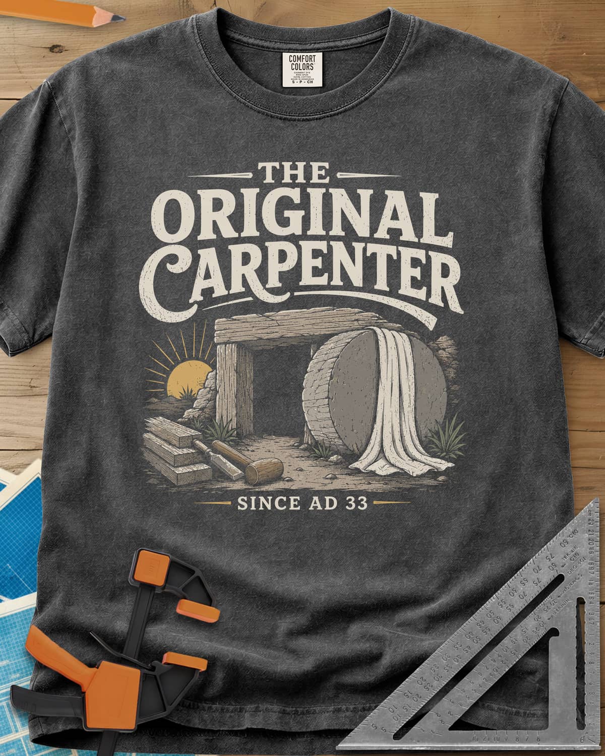 The Original Carpenter heavyweight tee in Pepper, an empty tomb at sunrise with planks, a mallet and a chisel