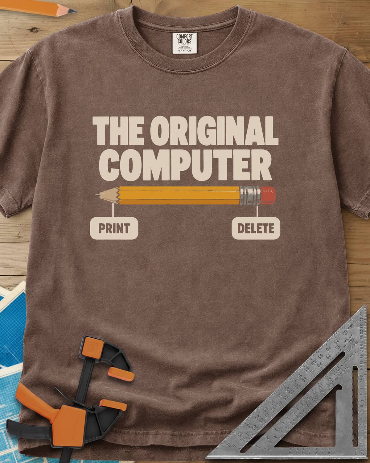 The Original Computer heavyweight tee in Espresso, a yellow pencil labeled PRINT at the point and DELETE at the eraser