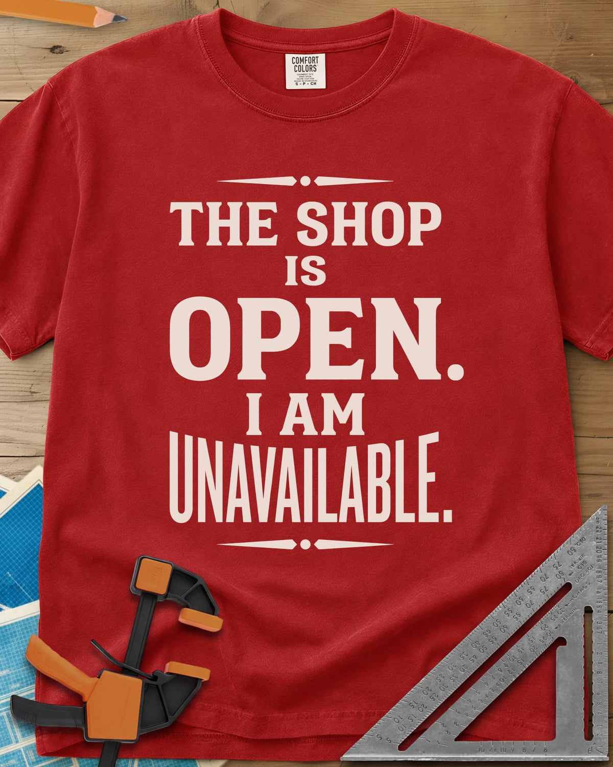 The Shop Is Open I Am Unavailable heavyweight tee in Red, stacked serif lettering between two ornamental dividers
