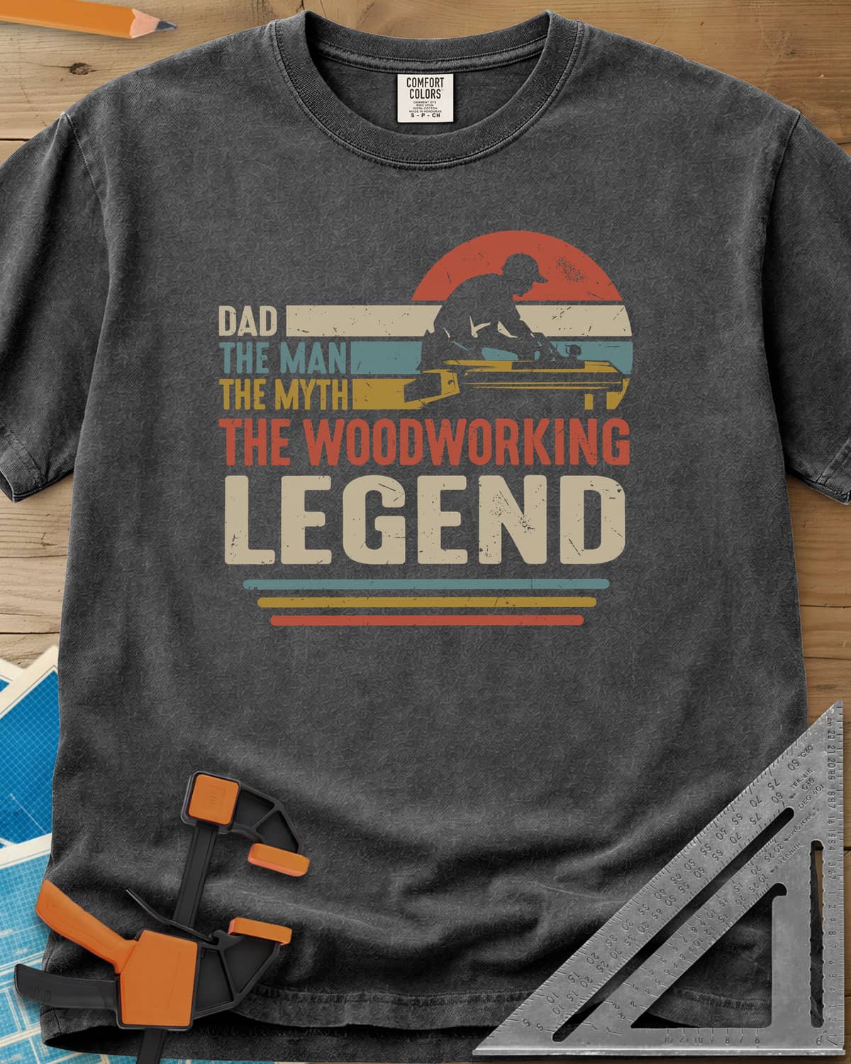 The Woodworking Legend heavyweight tee in Pepper, retro sunset stripes behind a silhouetted woodworker at his bench