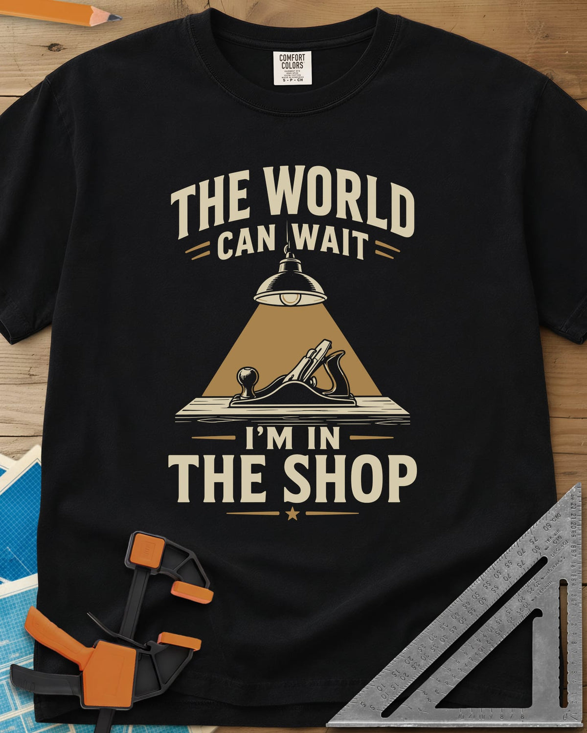 The World Can Wait I'm In The Shop heavyweight tee in Black, a hand plane under a hanging shop lamp's cone of light