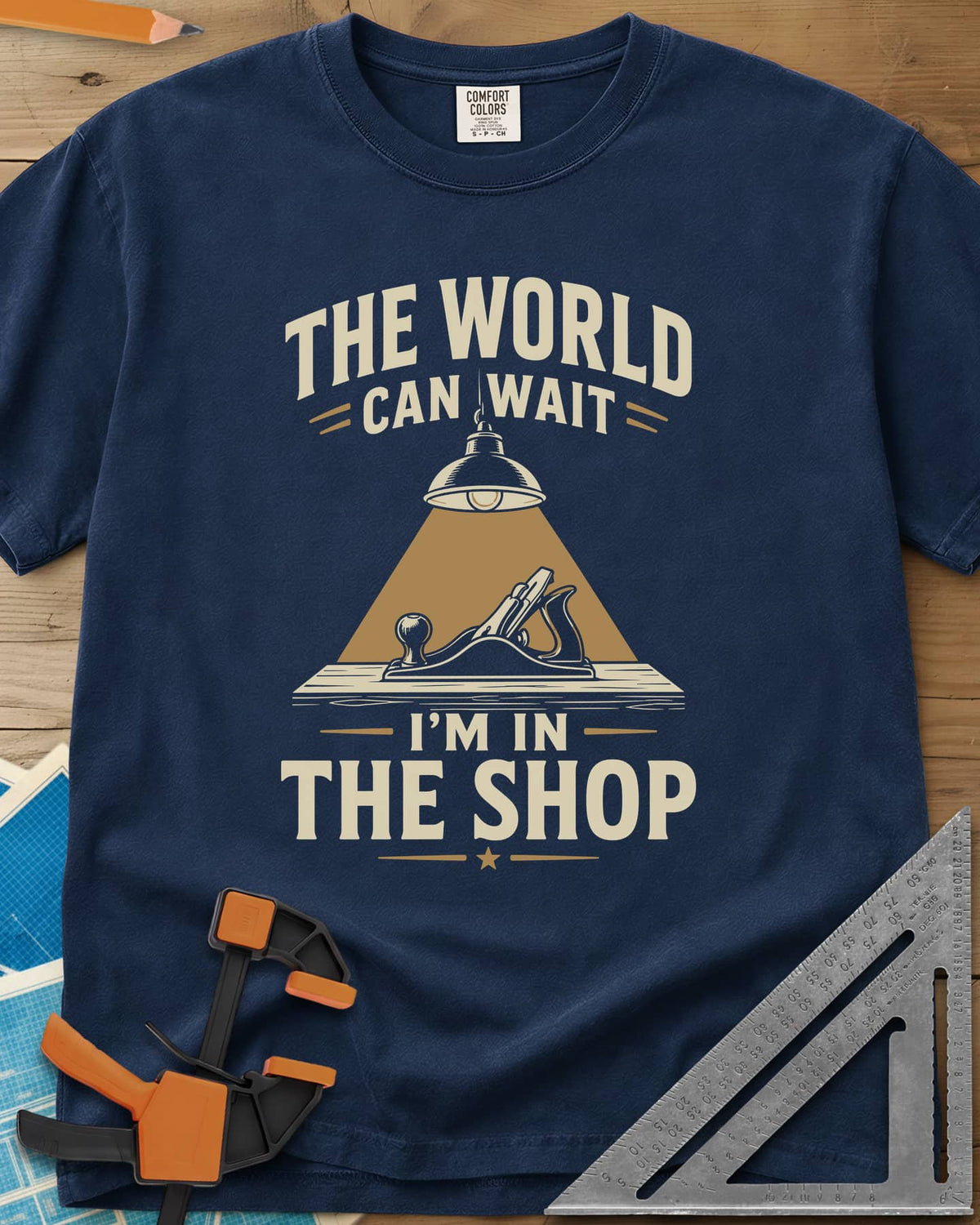 The World Can Wait I'm In The Shop heavyweight tee in Navy, a hand plane under a hanging shop lamp's cone of light