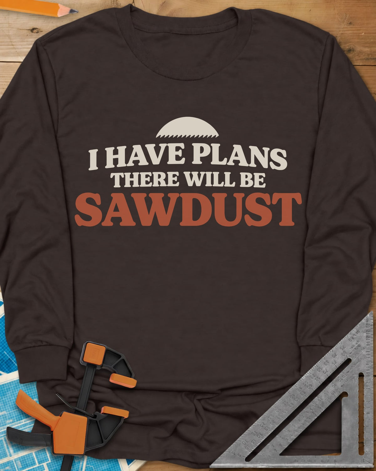There Will Be Sawdust long sleeve shirt in Dark Chocolate, half a toothed saw blade above rounded, bold lettering