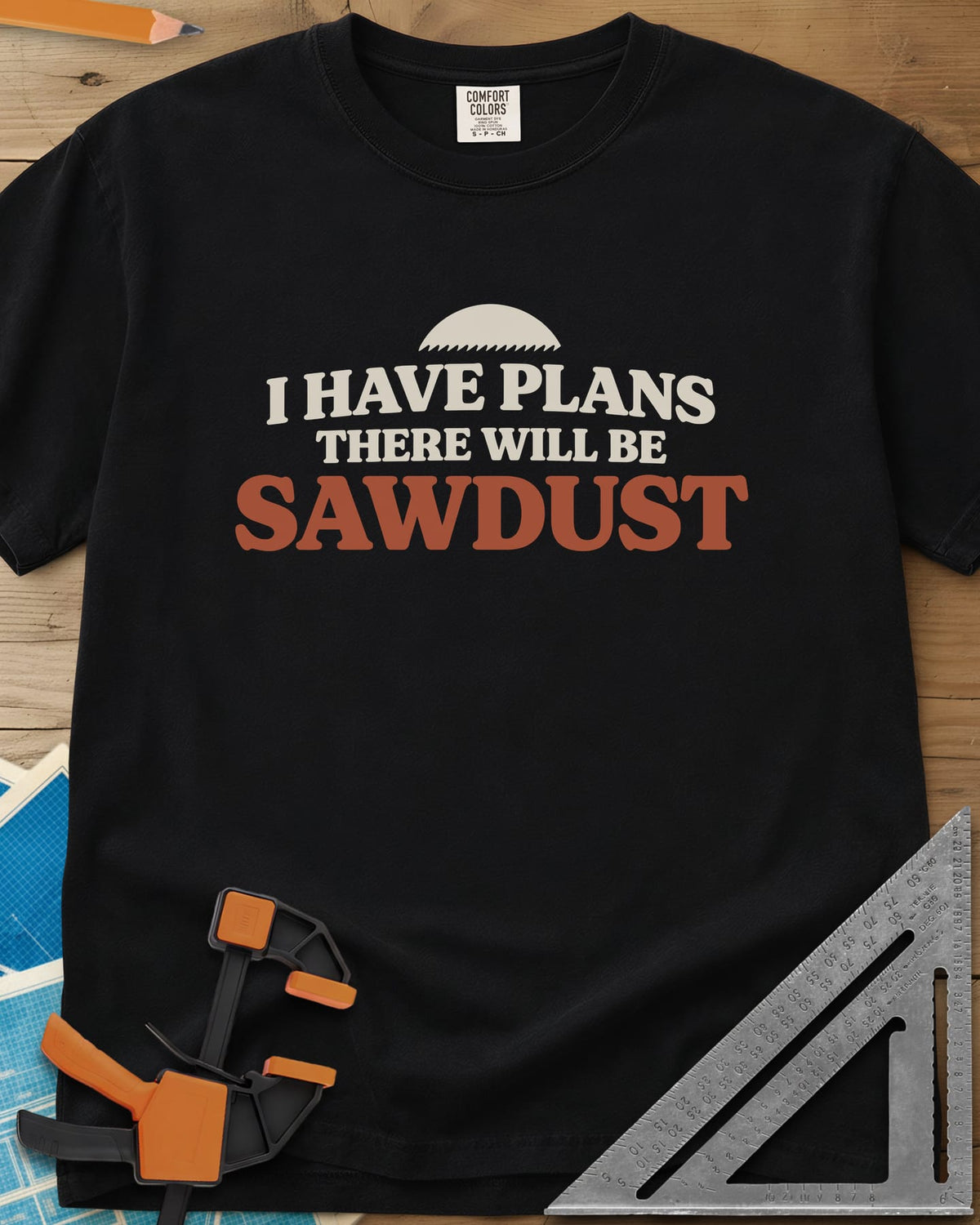 There Will Be Sawdust heavyweight tee in Black, half a toothed saw blade above rounded, bold lettering