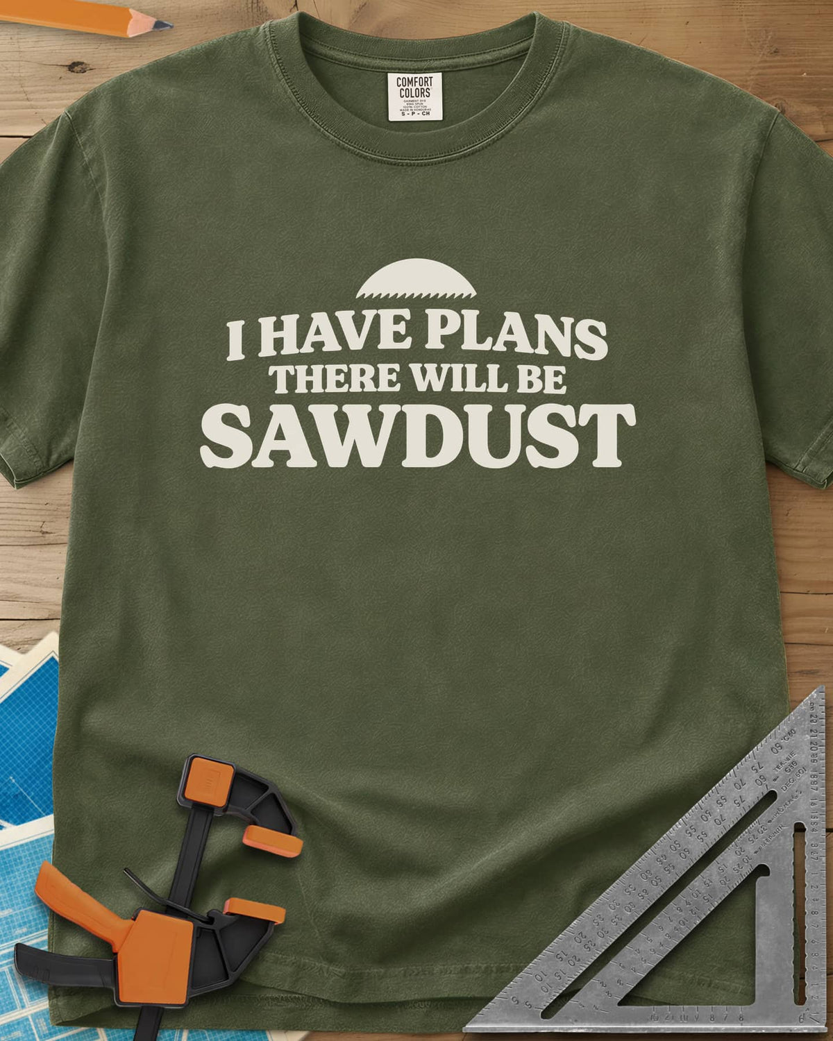 There Will Be Sawdust heavyweight tee in Hemp, half a toothed saw blade above rounded, bold lettering