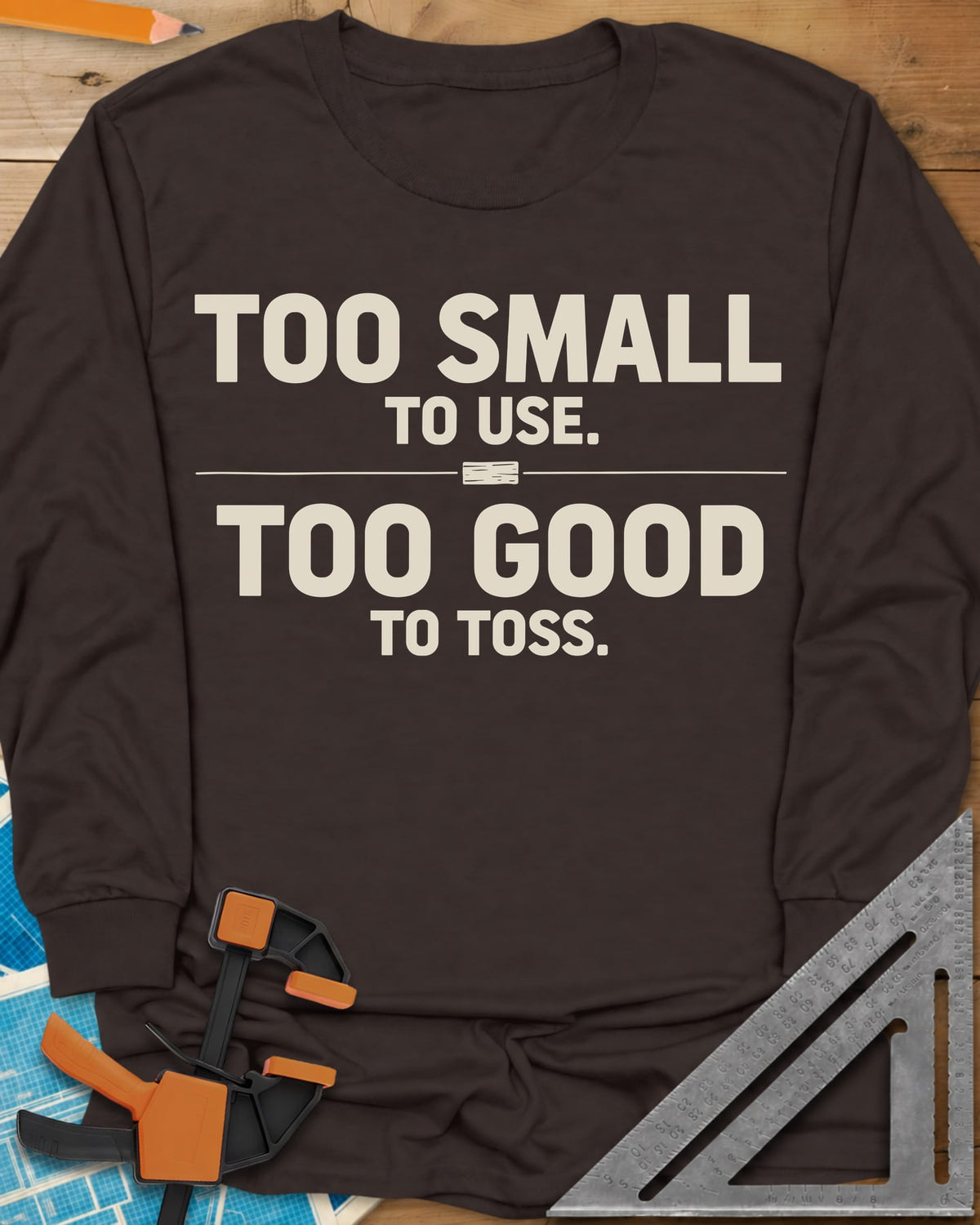 Too Small To Use Too Good To Toss long sleeve shirt in Dark Chocolate, two-line slogan split by a rule with a tiny wood