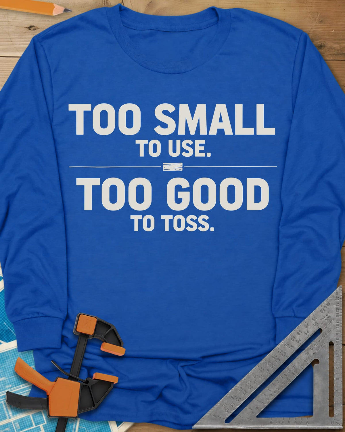 Too Small To Use Too Good To Toss long sleeve shirt in Royal, two-line slogan split by a rule with a tiny wood offcut