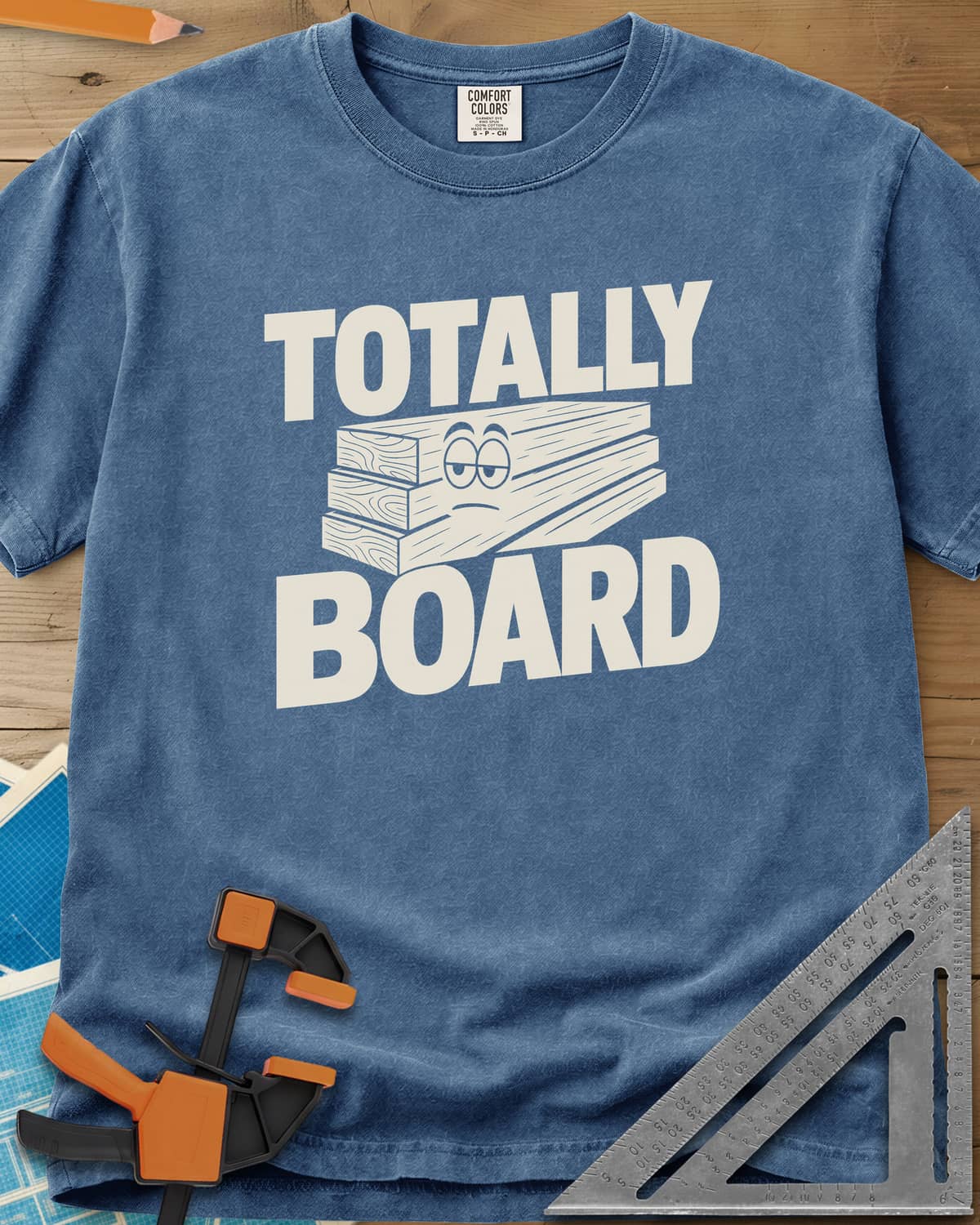 Totally Board heavyweight tee in Blue Jean, a stack of three planks wearing a bored, half-lidded face