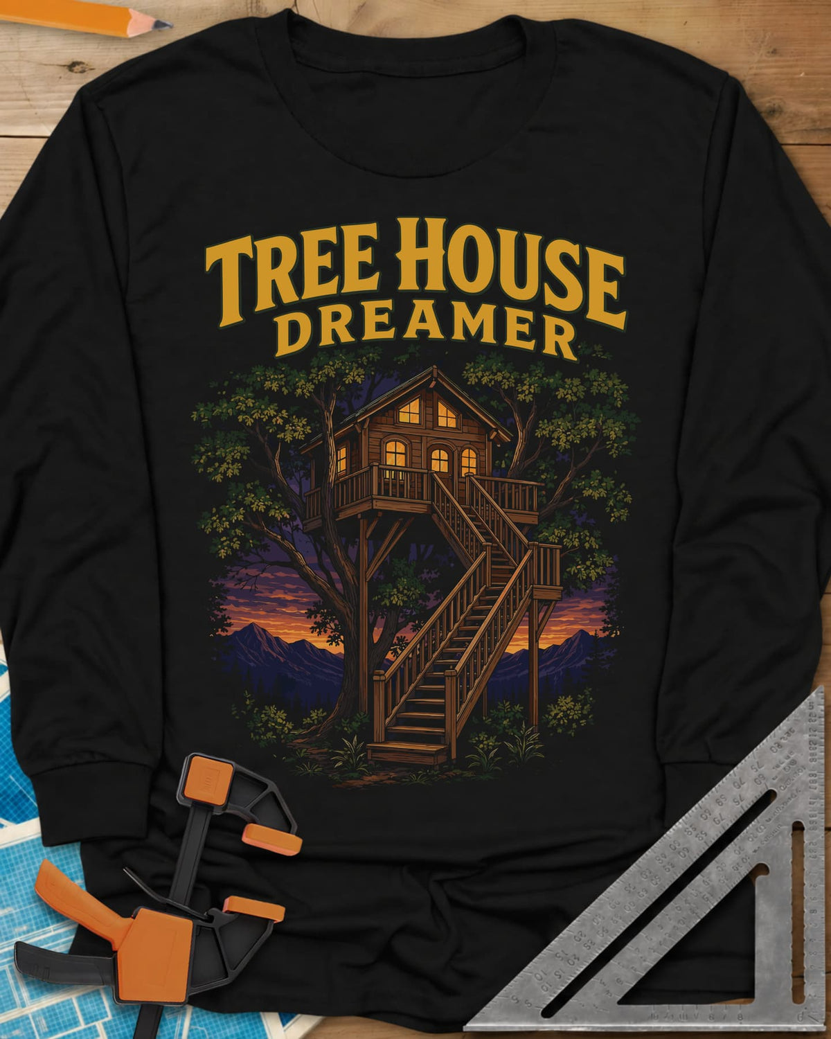 Tree House Dreamer long sleeve shirt in Black, a glowing wooden treehouse with a long staircase at sunset