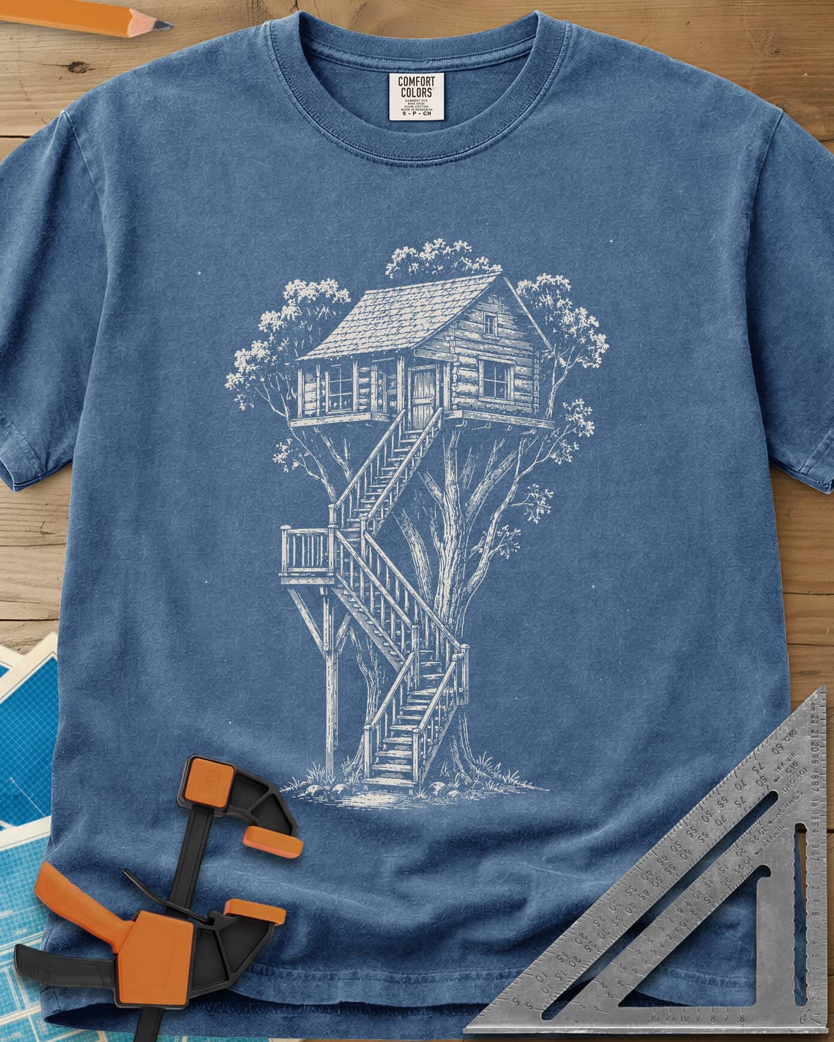 Treehouse Dream Build heavyweight tee in Blue Jean, ink-style log cabin treehouse with a zigzag staircase