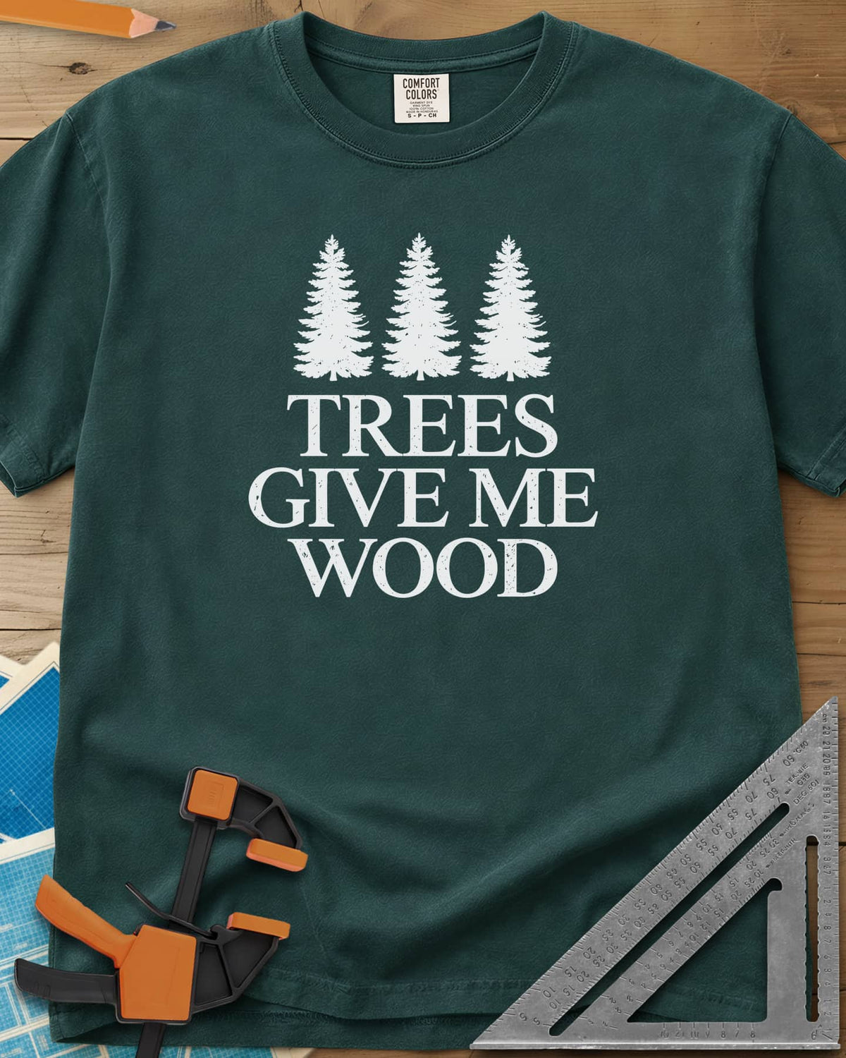 Trees Give Me Wood heavyweight tee in Blue Spruce, three evergreen trees above worn serif lettering