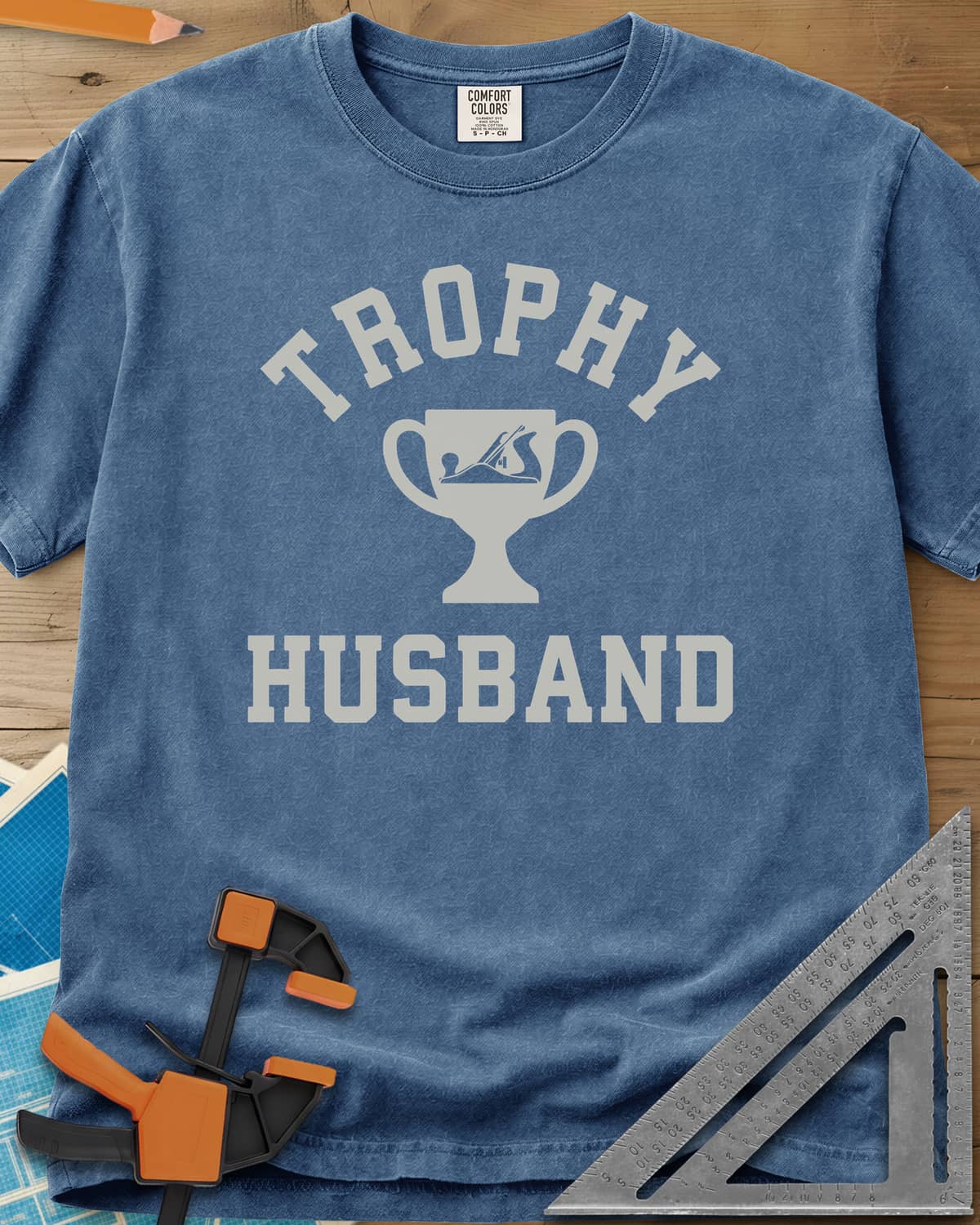 Trophy Husband Woodworker heavyweight tee in Blue Jean, varsity lettering around a trophy cup with a hand plane on it