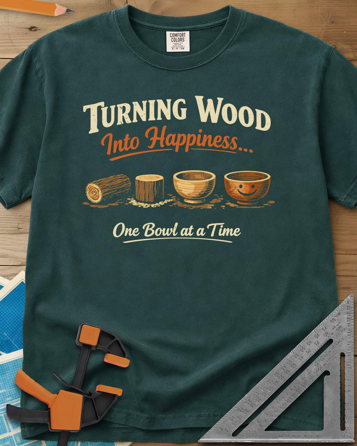 Turning Happiness heavyweight tee in Blue Spruce, a log, a stump, a plain bowl and a bowl with a smiley face