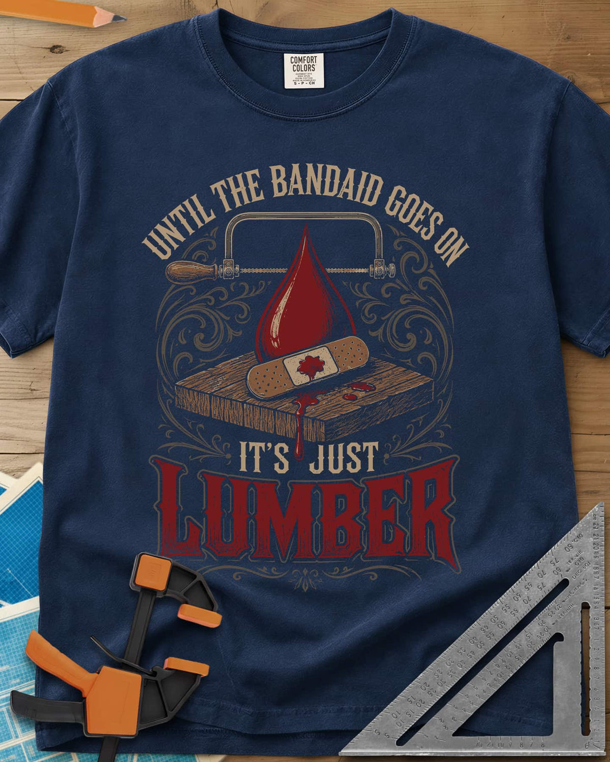 Until The Bandaid Goes On It's Just Lumber heavyweight tee in Navy, frame saw, red drop and a bandaid on a board with