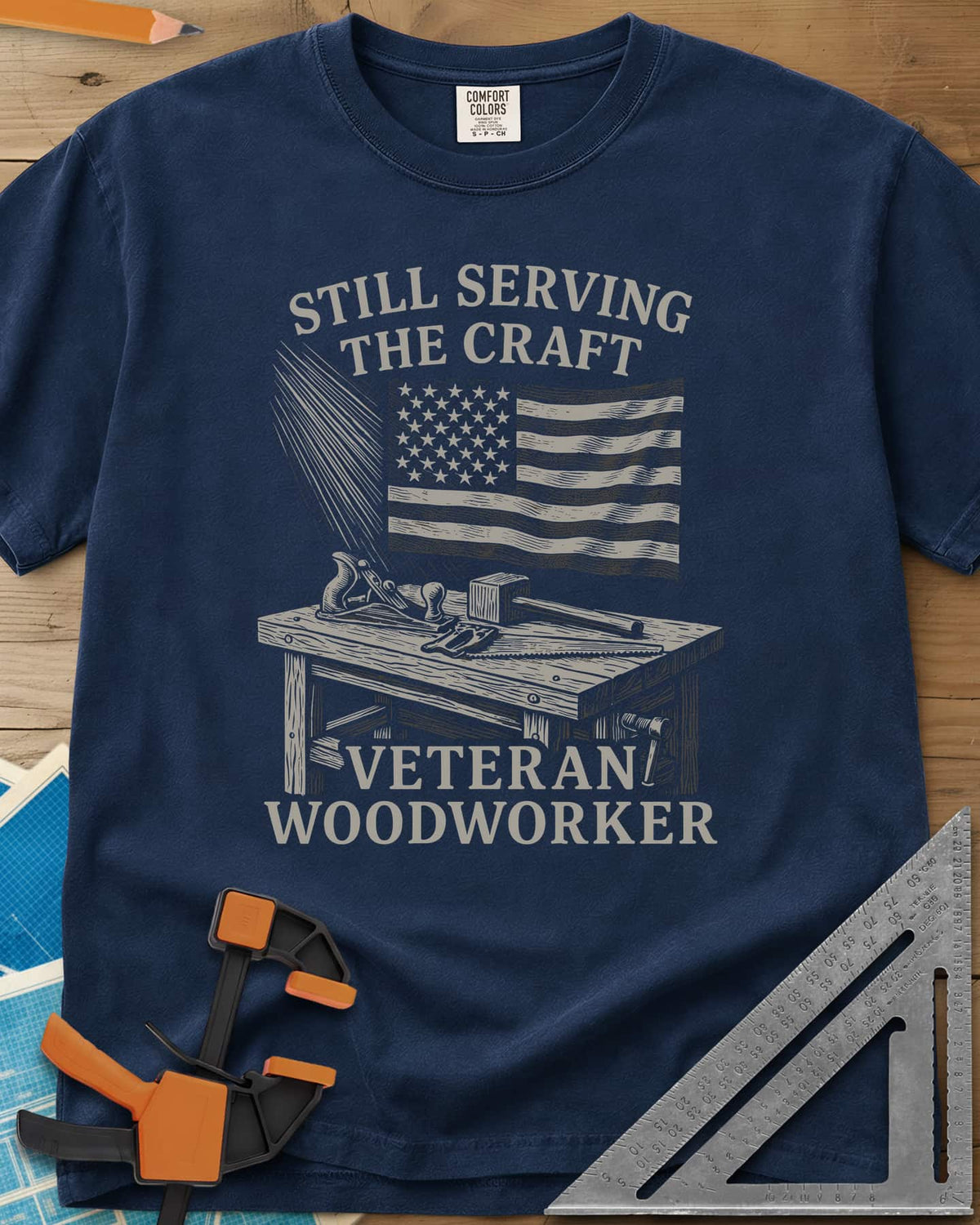 Veteran Woodworker heavyweight tee in Navy, an American flag over a workbench with a plane, mallet and saw