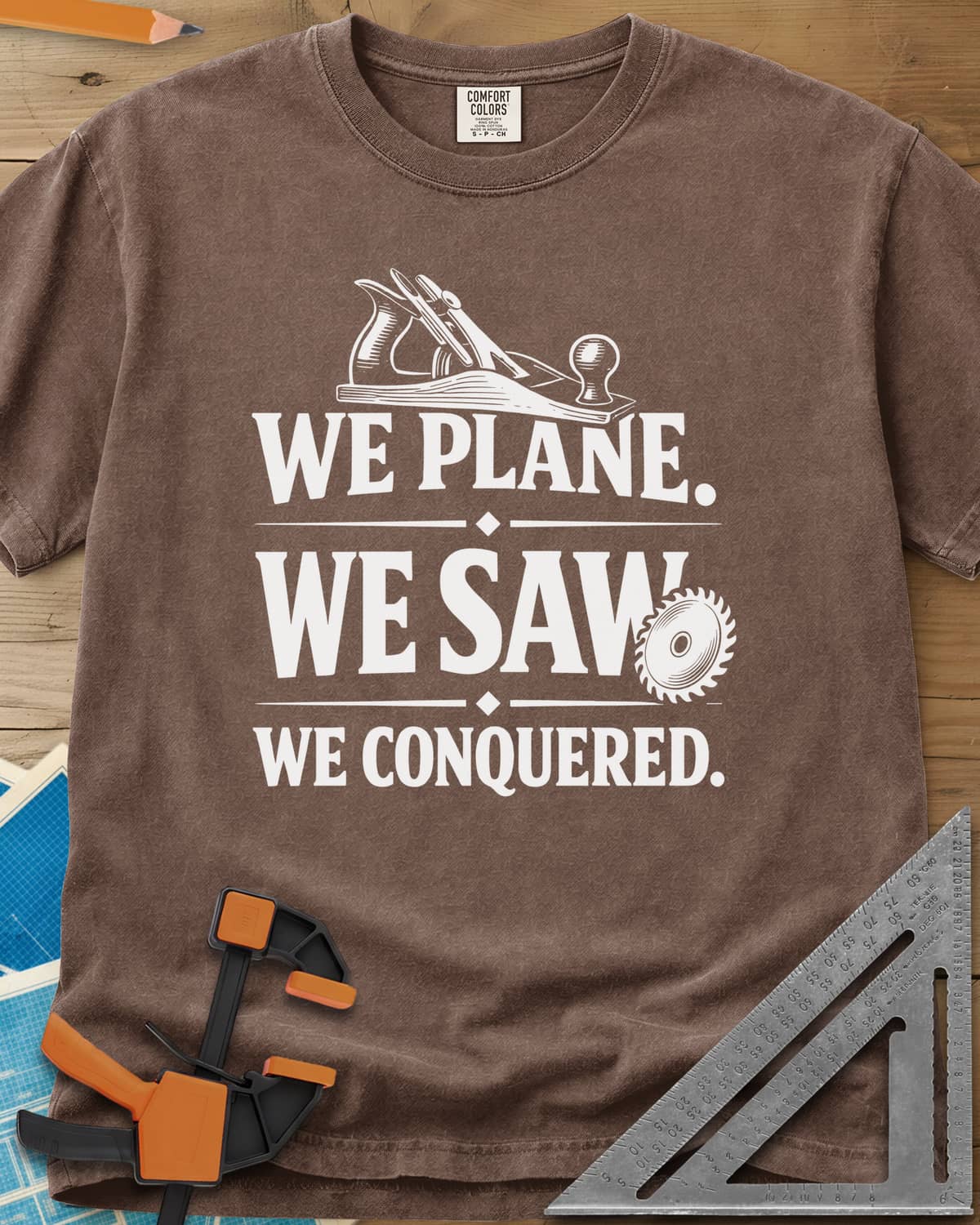 We Plane, We Saw heavyweight tee in Espresso, a hand plane and a saw blade framing a three-line slogan