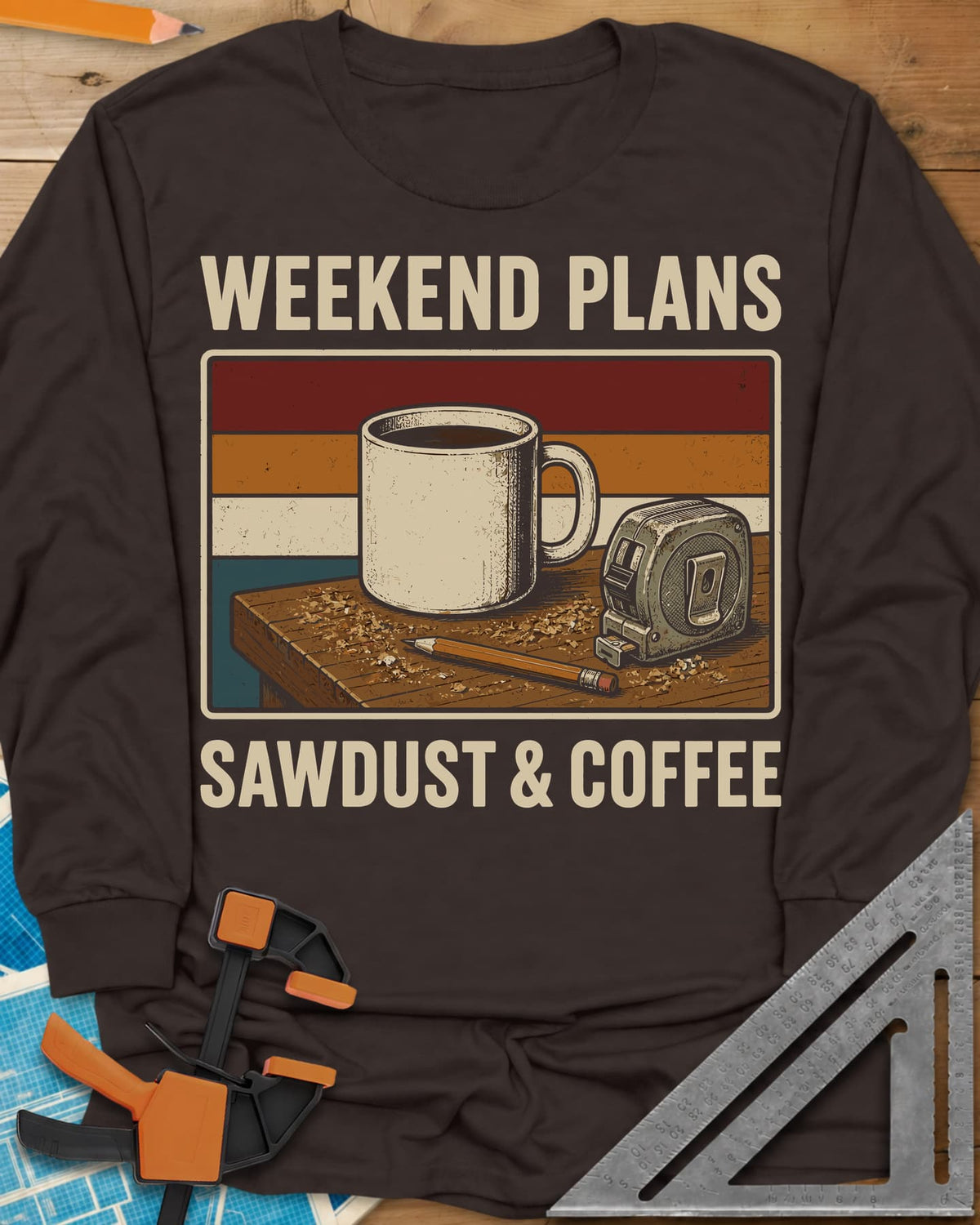 Weekend Plans Sawdust Coffee long sleeve shirt in Dark Chocolate, a coffee mug, tape measure and pencil on a sawdusty bench