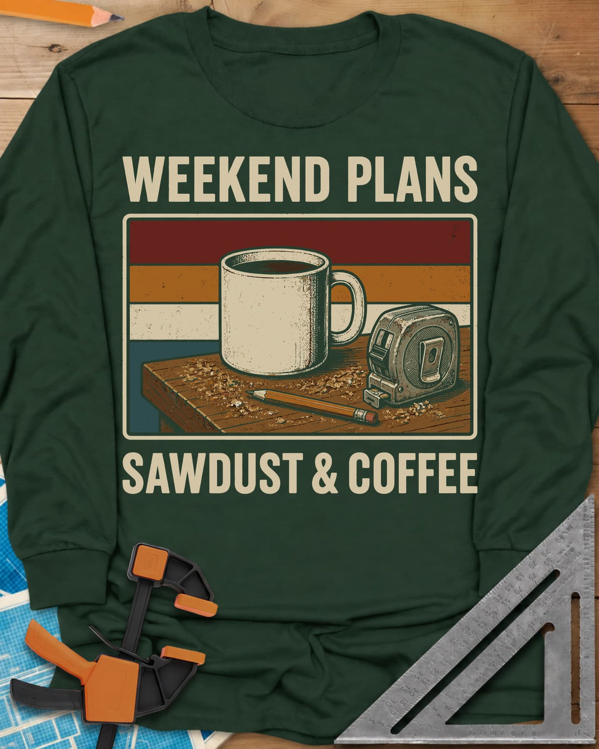 Weekend Plans Sawdust Coffee long sleeve shirt in Forest Green, a coffee mug, tape measure and pencil on a sawdusty bench