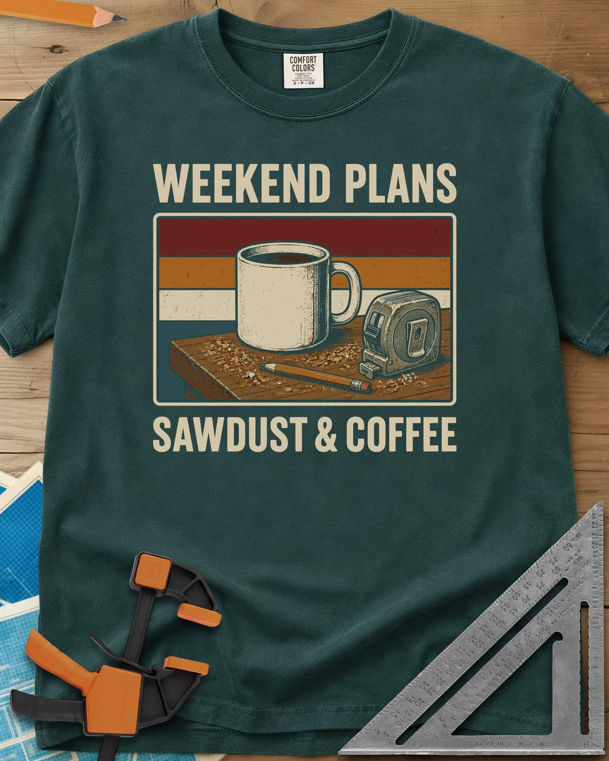 Weekend Plans Sawdust Coffee heavyweight tee in Blue Spruce, a coffee mug, tape measure and pencil on a sawdusty bench