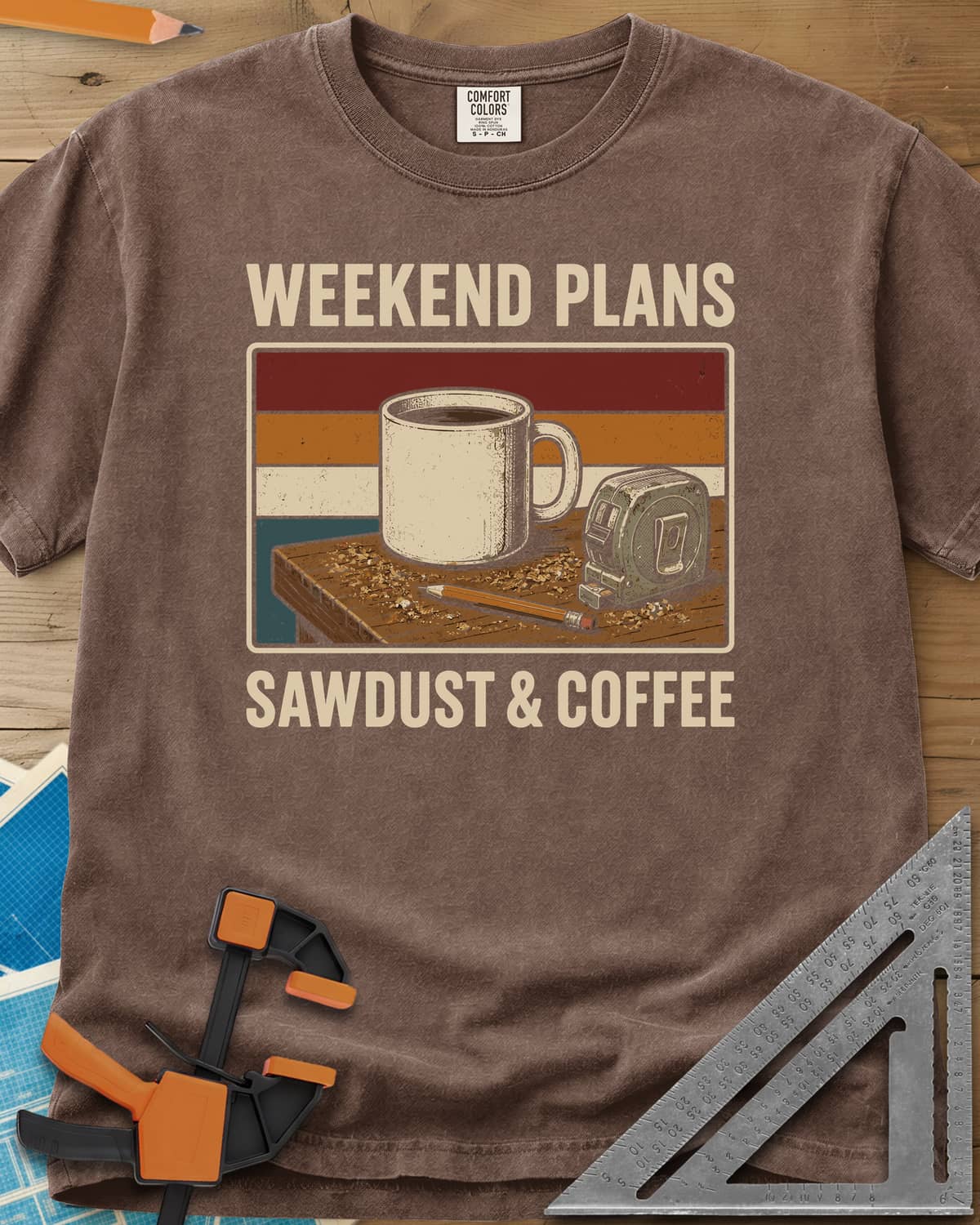 Weekend Plans Sawdust Coffee heavyweight tee in Espresso, a coffee mug, tape measure and pencil on a sawdusty bench