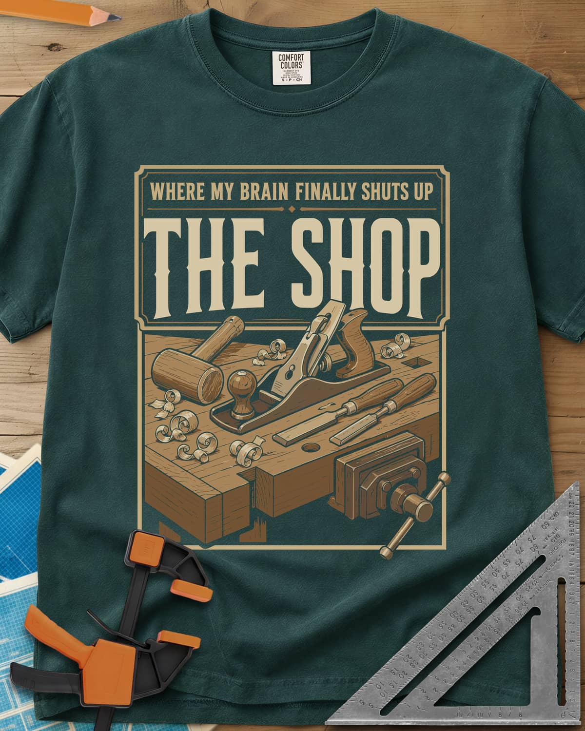 Where My Brain Finally Shuts Up heavyweight tee in Blue Spruce, a framed workbench poster with plane, mallet, chisels and