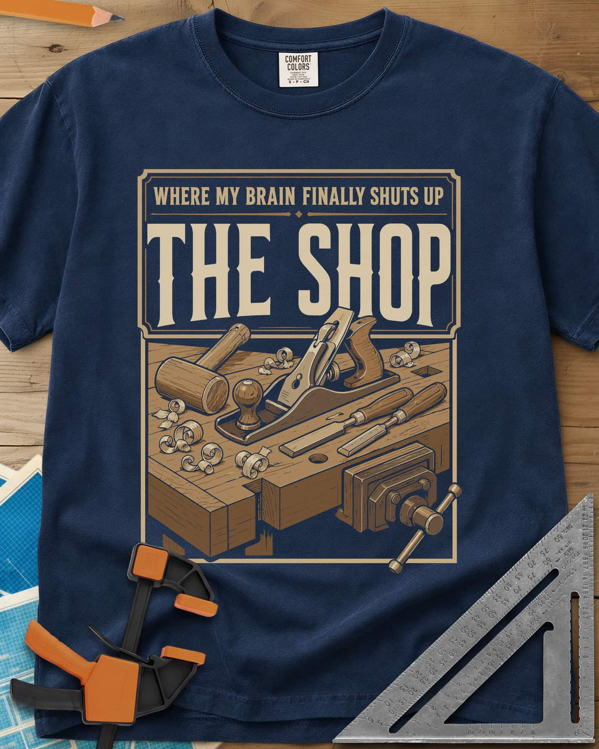 Where My Brain Finally Shuts Up heavyweight tee in Navy, a framed workbench poster with plane, mallet, chisels and vise