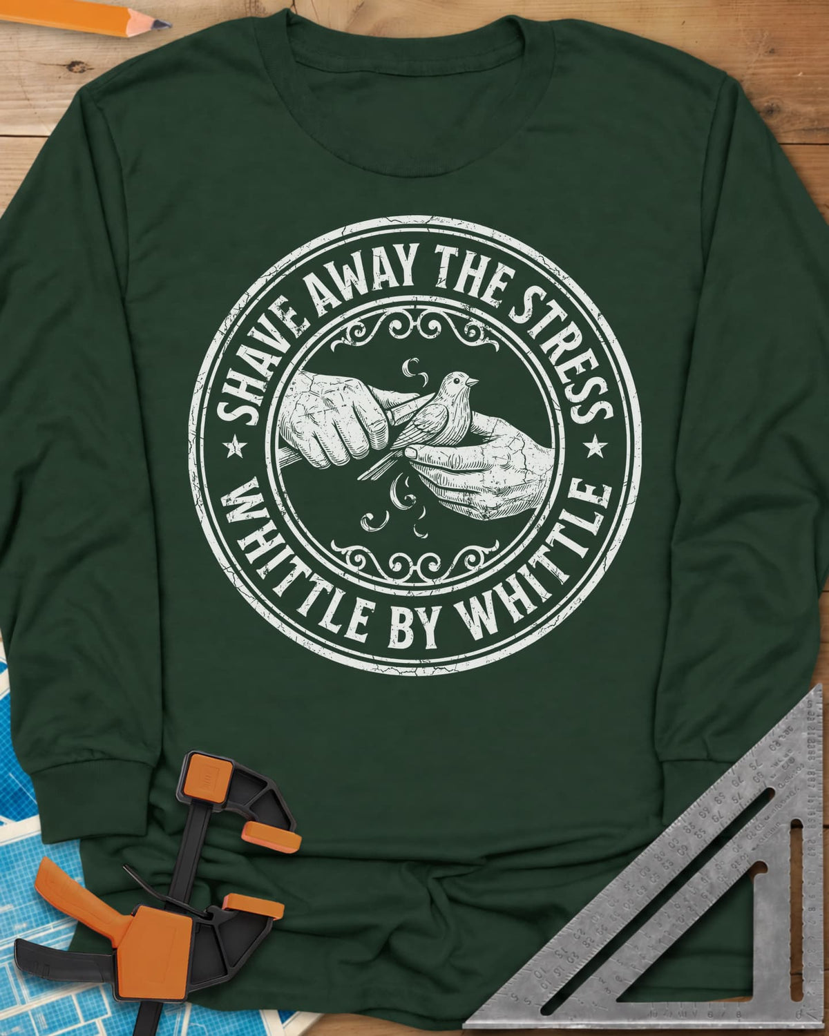 Whittle by Whittle long sleeve shirt in Forest Green, two hands whittling a small bird inside a round distressed badge