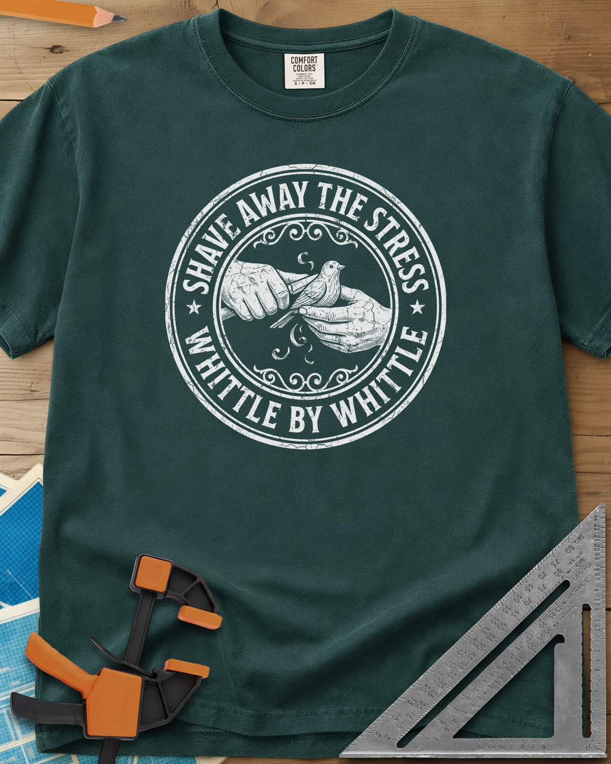 Whittle by Whittle heavyweight tee in Blue Spruce, two hands whittling a small bird inside a round distressed badge