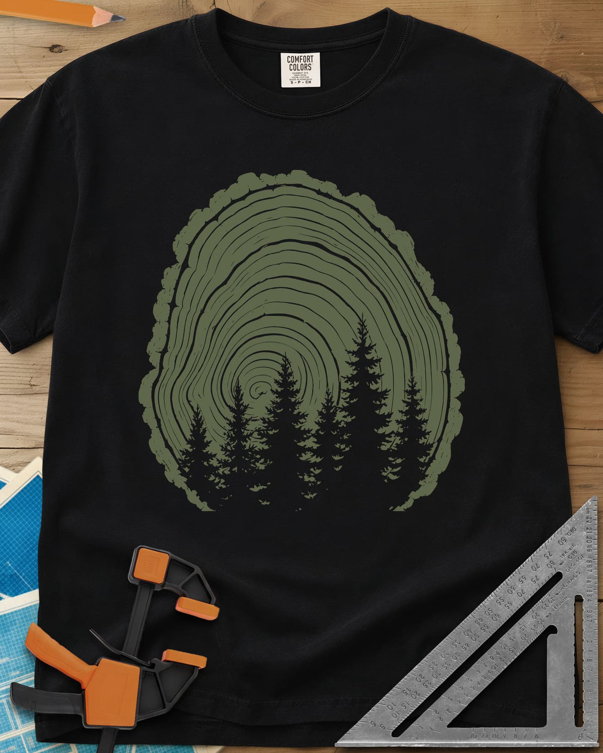 Wood Grain Forest heavyweight tee in Black, cut log tree rings with a stand of pine trees inside