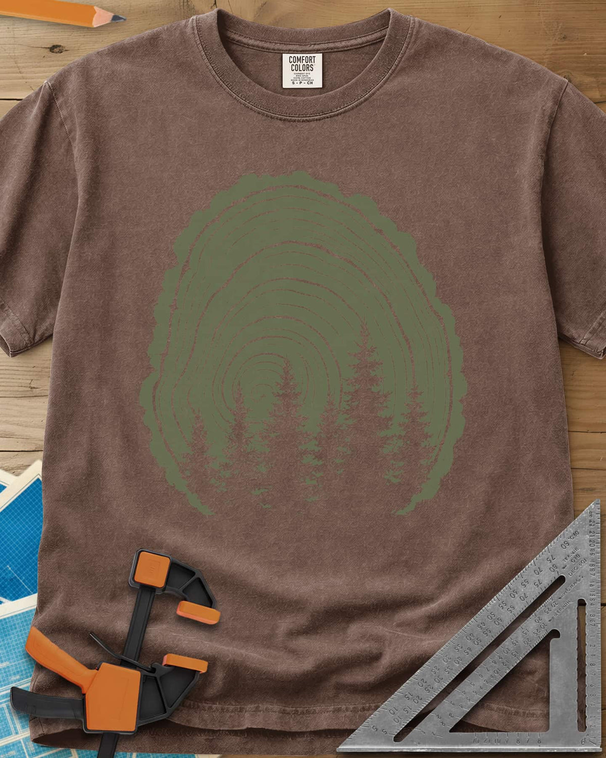 Wood Grain Forest heavyweight tee in Espresso, cut log tree rings with a stand of pine trees inside