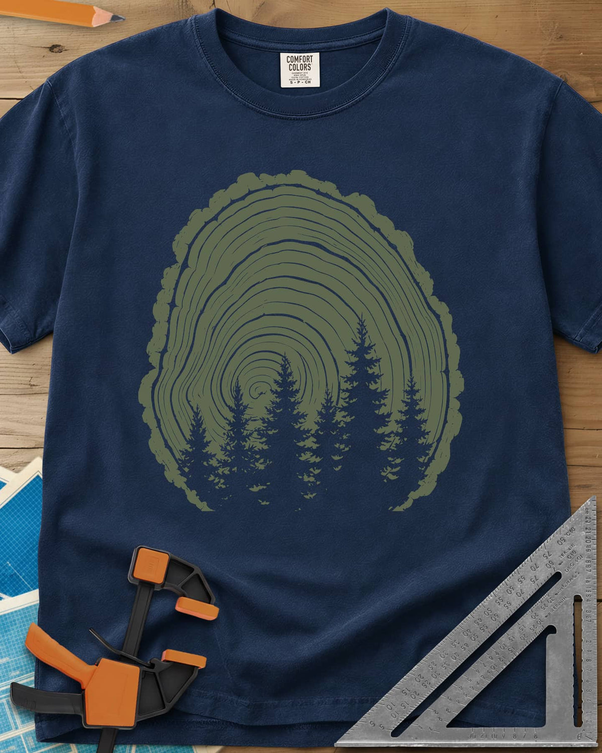 Wood Grain Forest heavyweight tee in Navy, cut log tree rings with a stand of pine trees inside